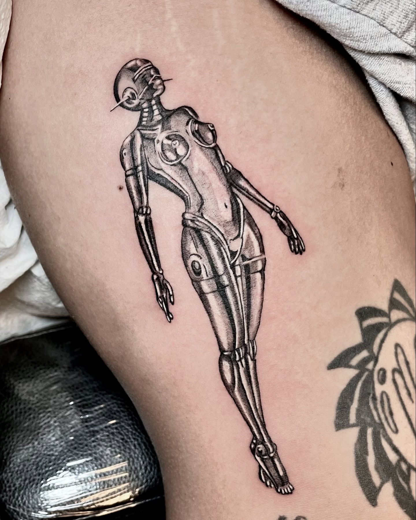 Android black and grey tattoo on the thigh by Tattoo Artist