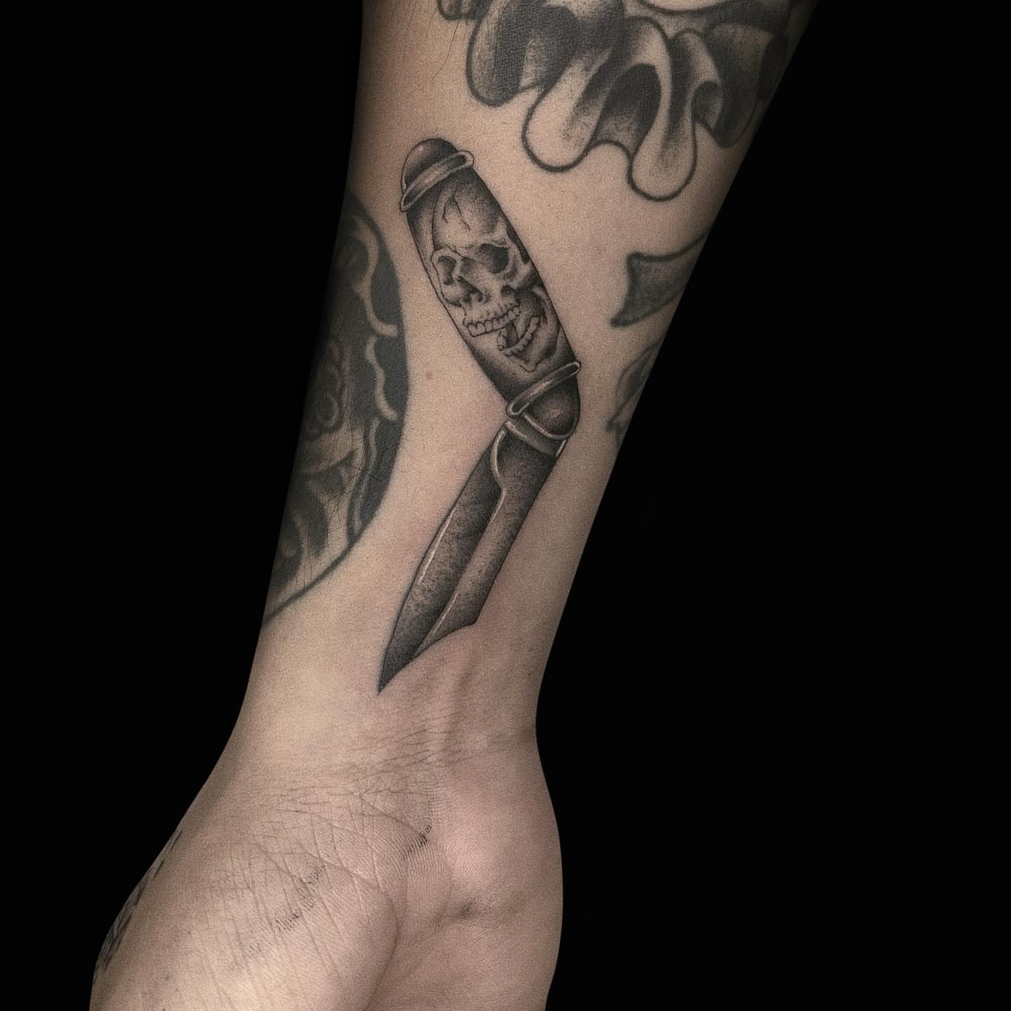 Knife with skull realism tattoo on the forearm by Jason
