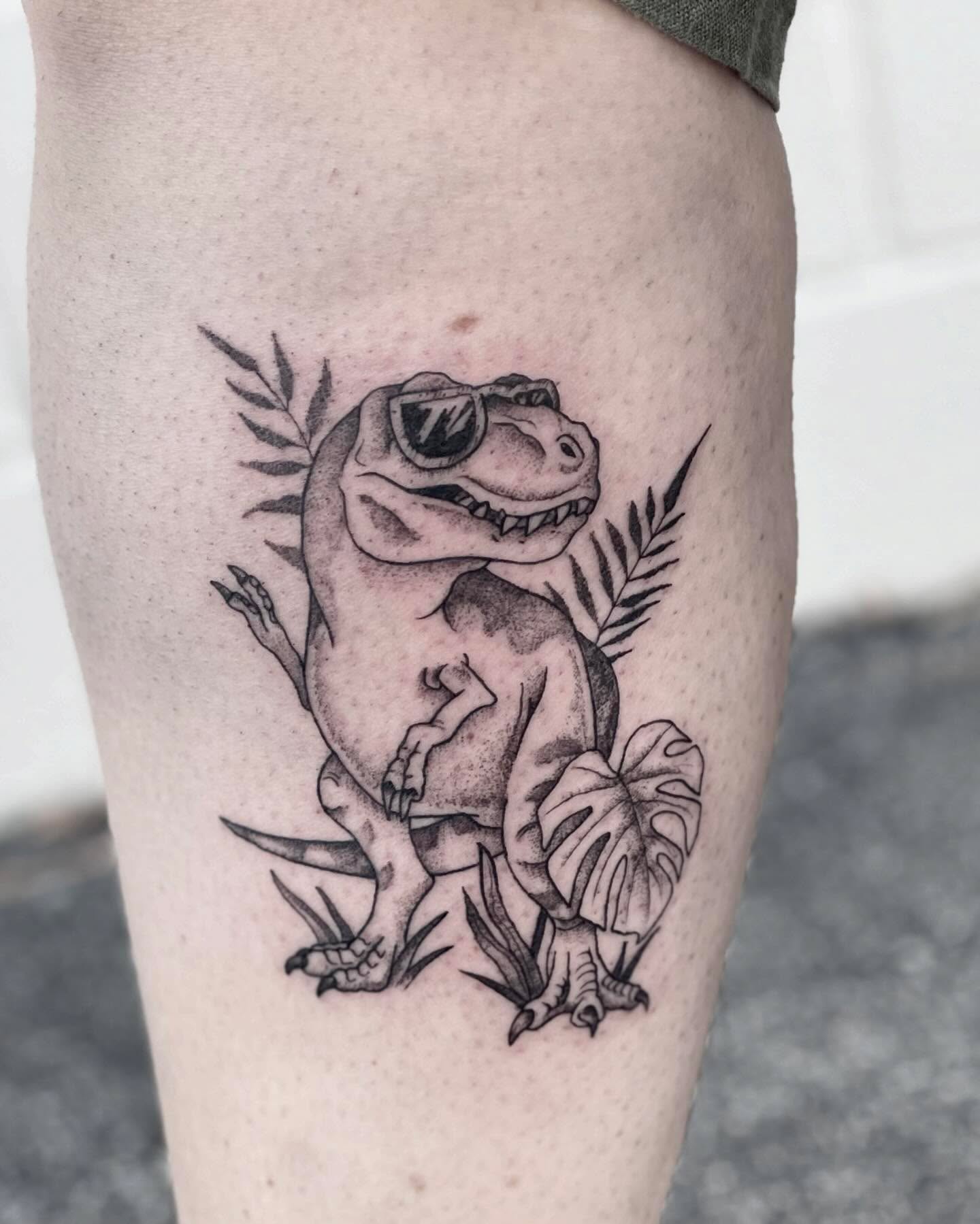 Dinosaur black and grey tattoo on the thigh by Katie Stacy