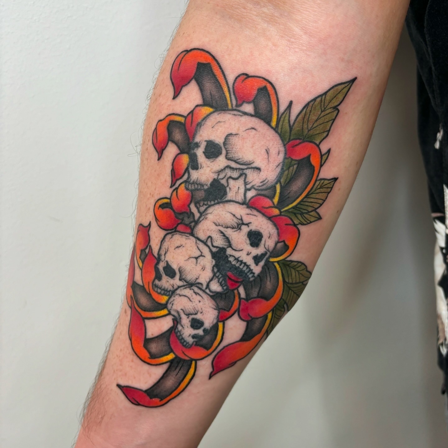 Skulls and jester hat American traditional tattoo on the forearm by Ryan Walker