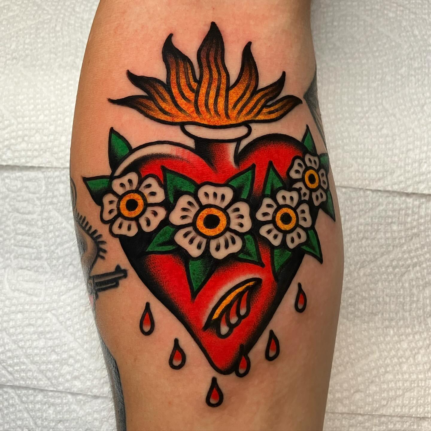 Heart with flowers American traditional tattoo on the forearm by John Lemon