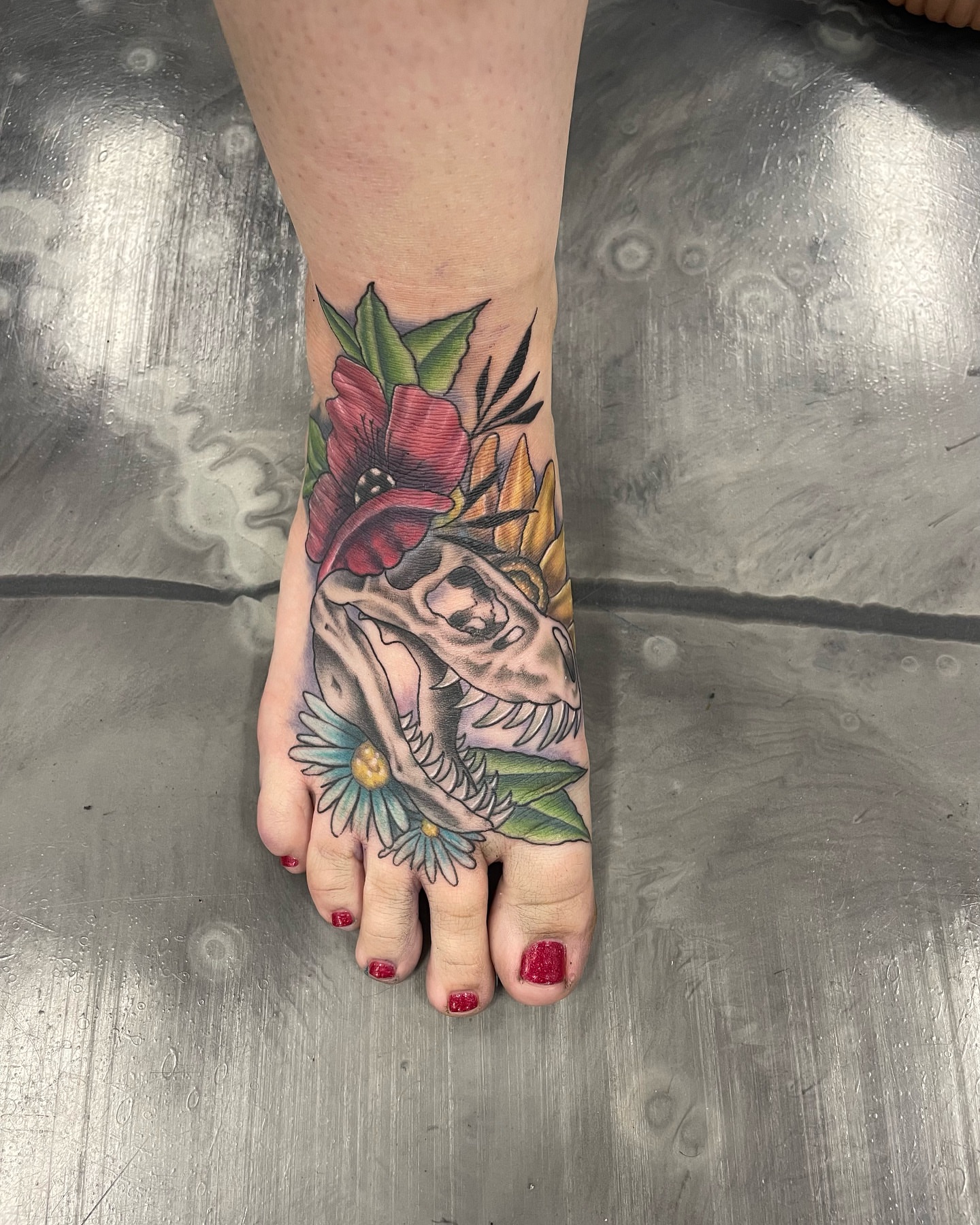 Skull and flowers American traditional tattoo on the foot by Brandon Anderson
