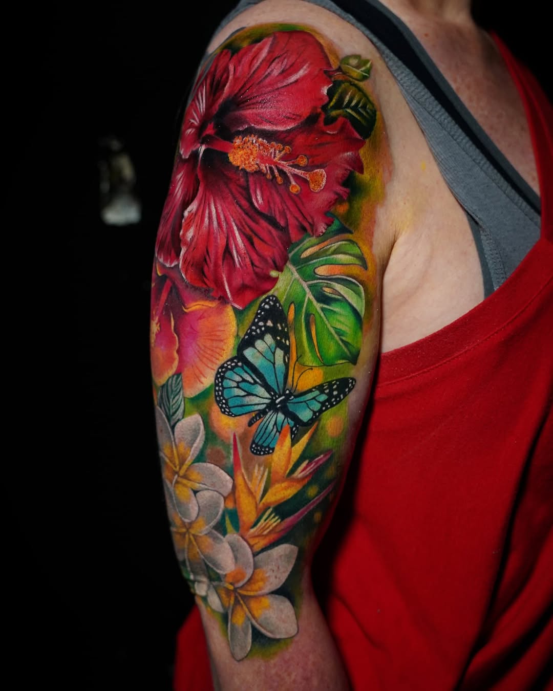 Hibiscus flower and butterfly watercolor tattoo on the upper arm by Su Kang