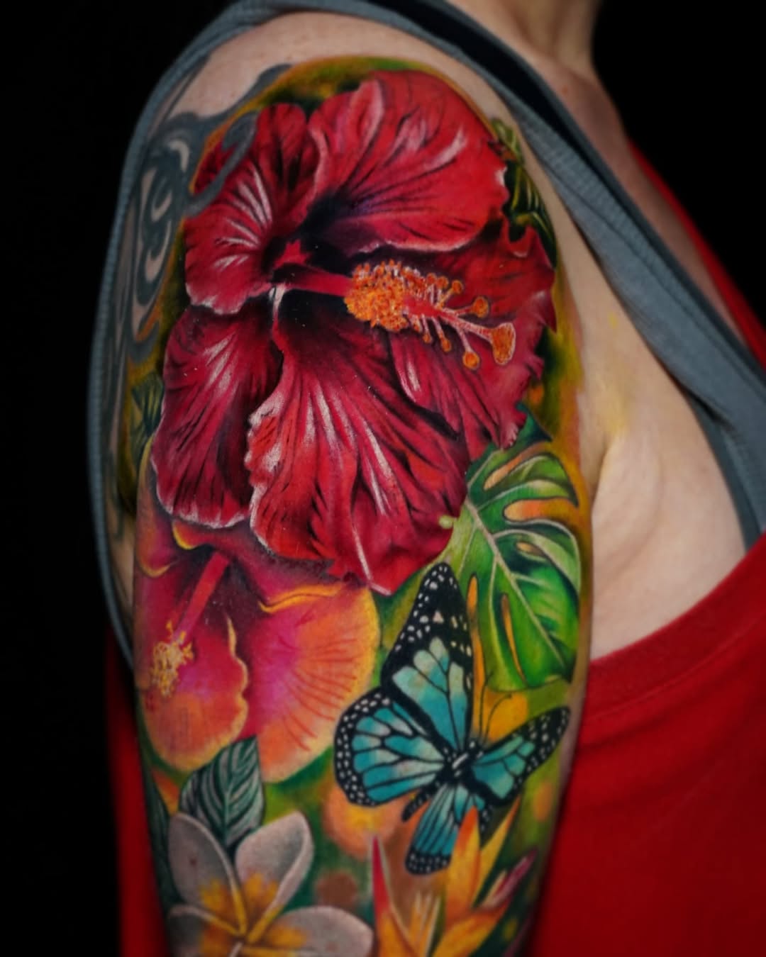 Hibiscus flowers and butterfly neo-traditional tattoo on the upper arm by Su Kang