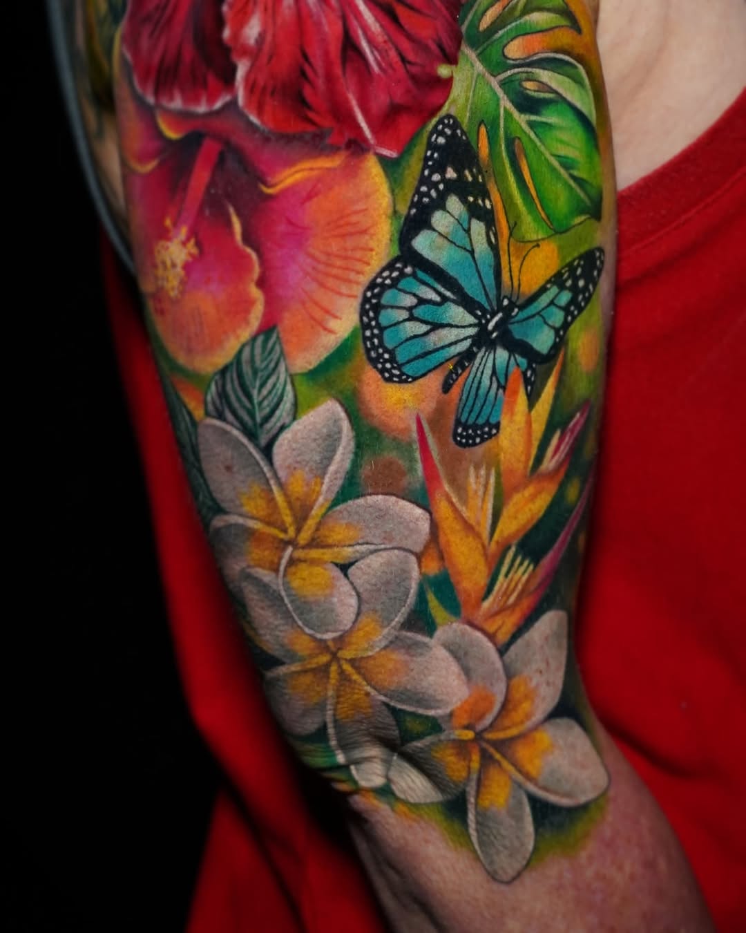 Tropical flowers and butterfly watercolor tattoo on the forearm by Su Kang