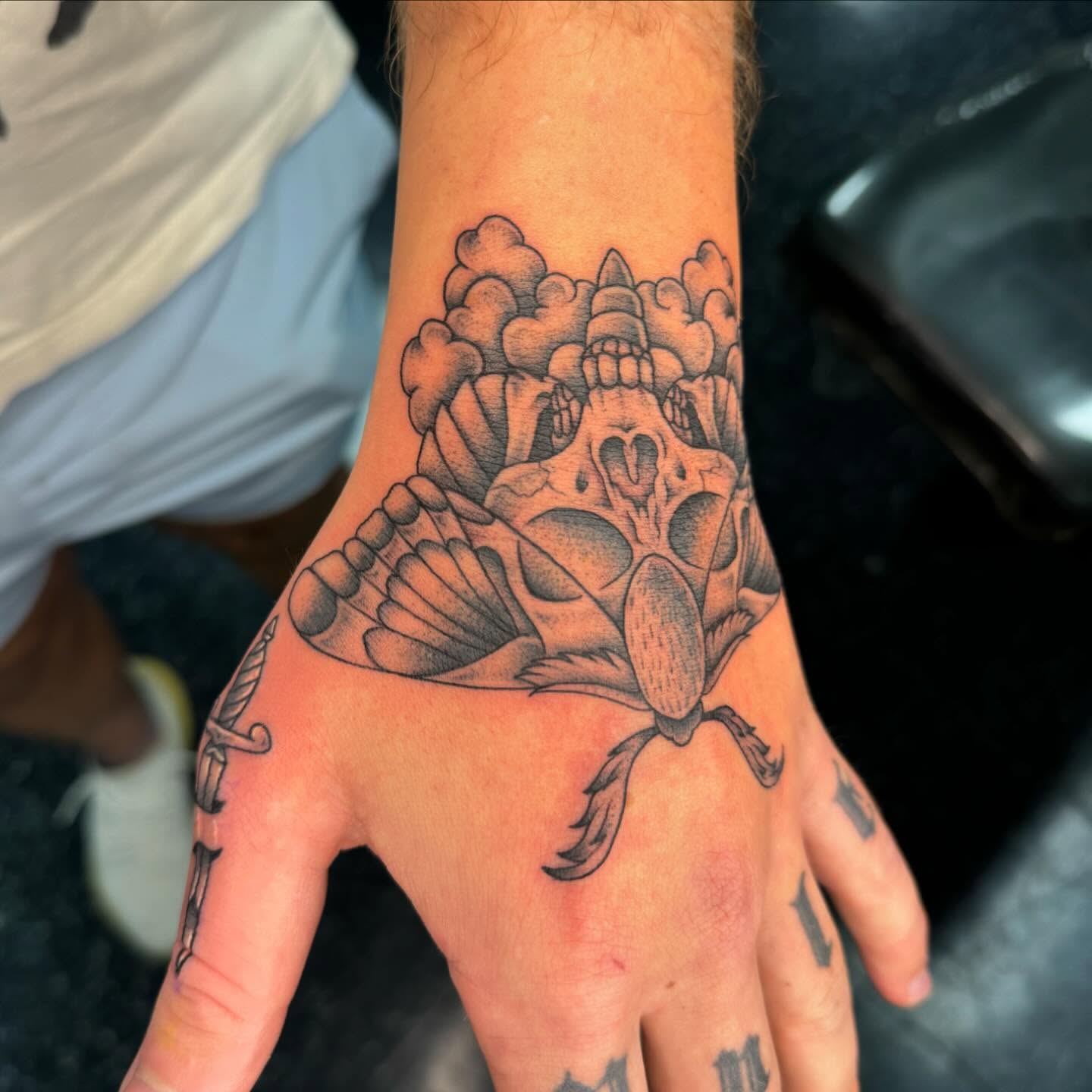 Skull and butterfly black and grey tattoo on the hand by Cory Perry-Servellon