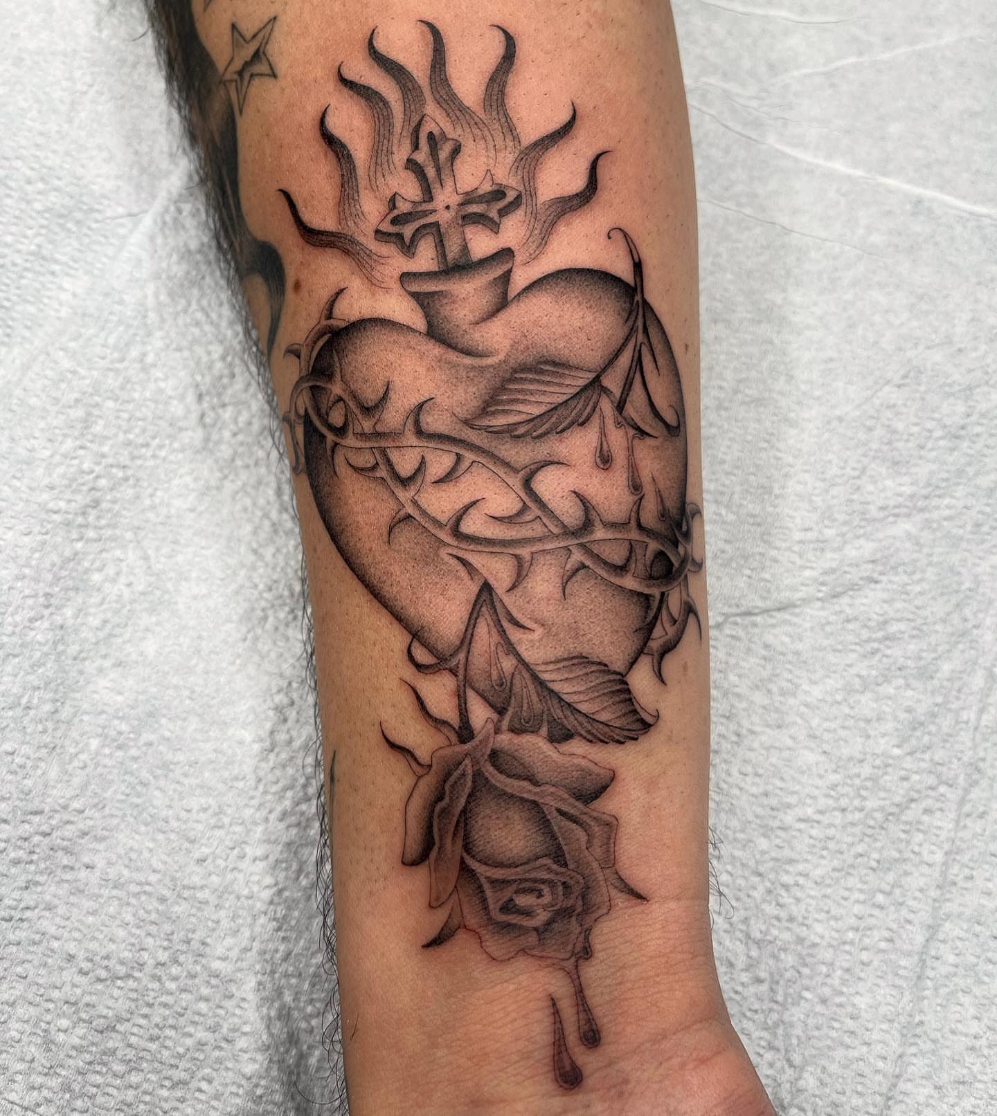 Heart with cross and rose realism tattoo on the forearm by Tiyanna Garlic