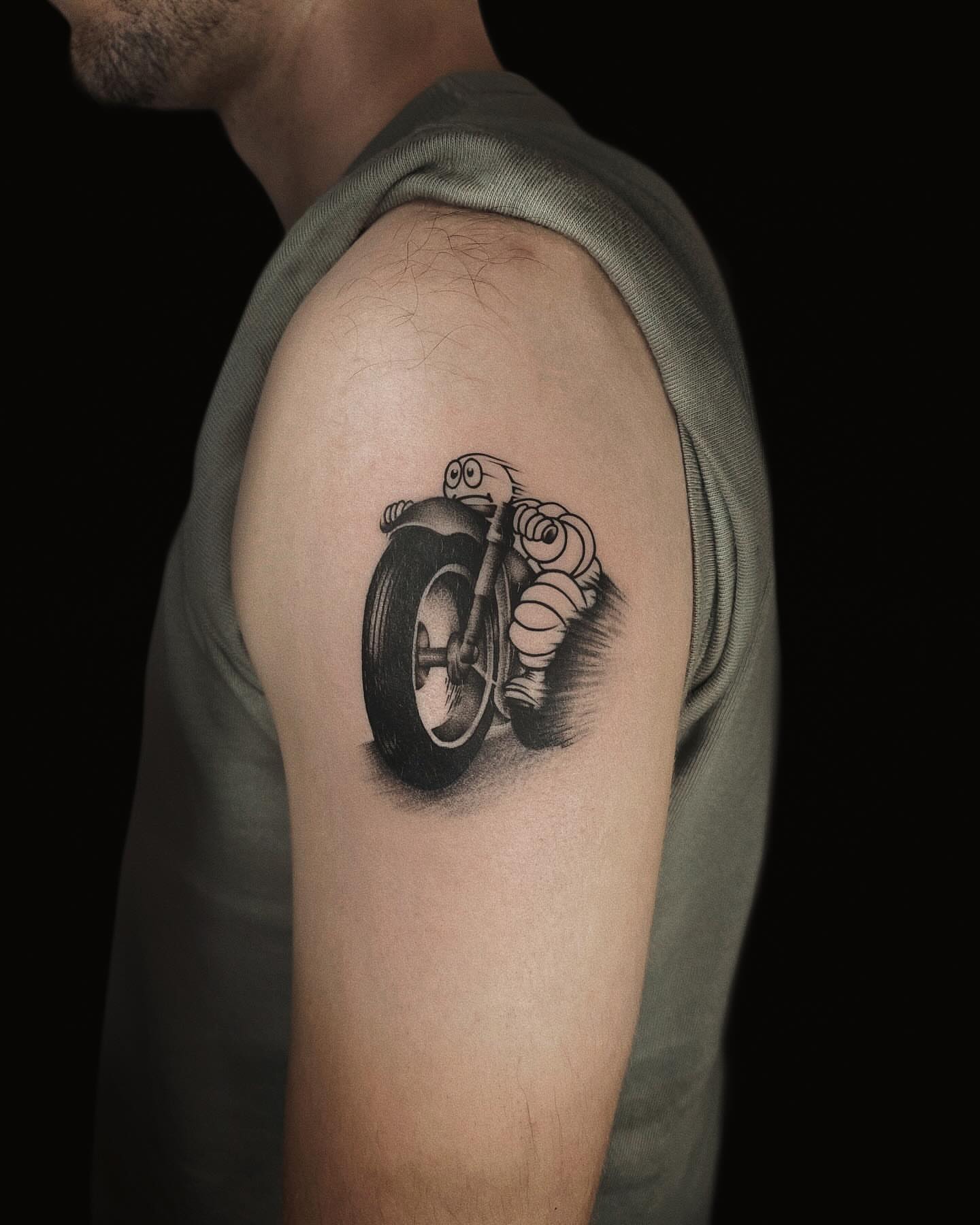 Motorcycle rider black and grey tattoo on the upper arm by Jason