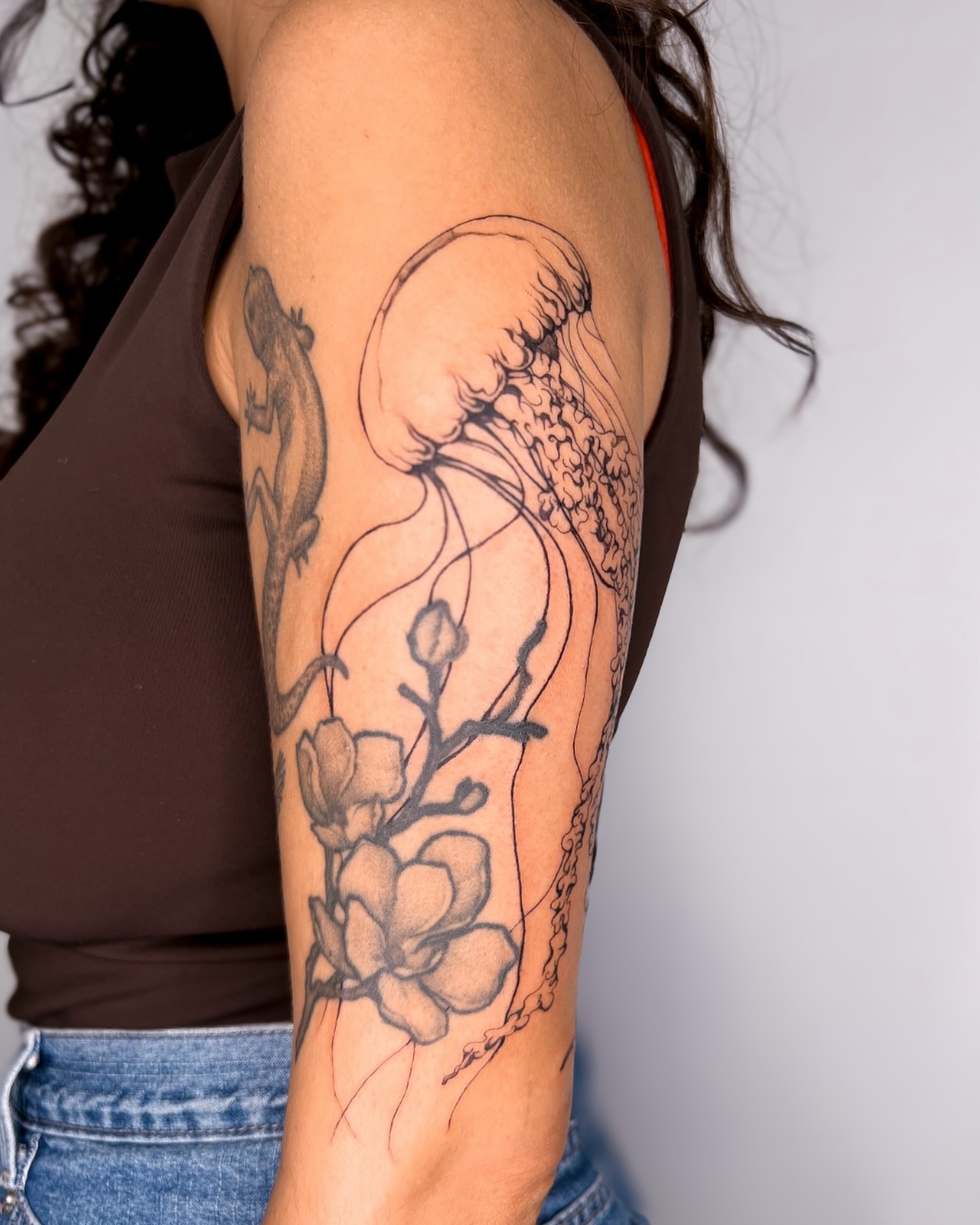 Jellyfish and flowers realism tattoo on the forearm by ᴀmb⃘er