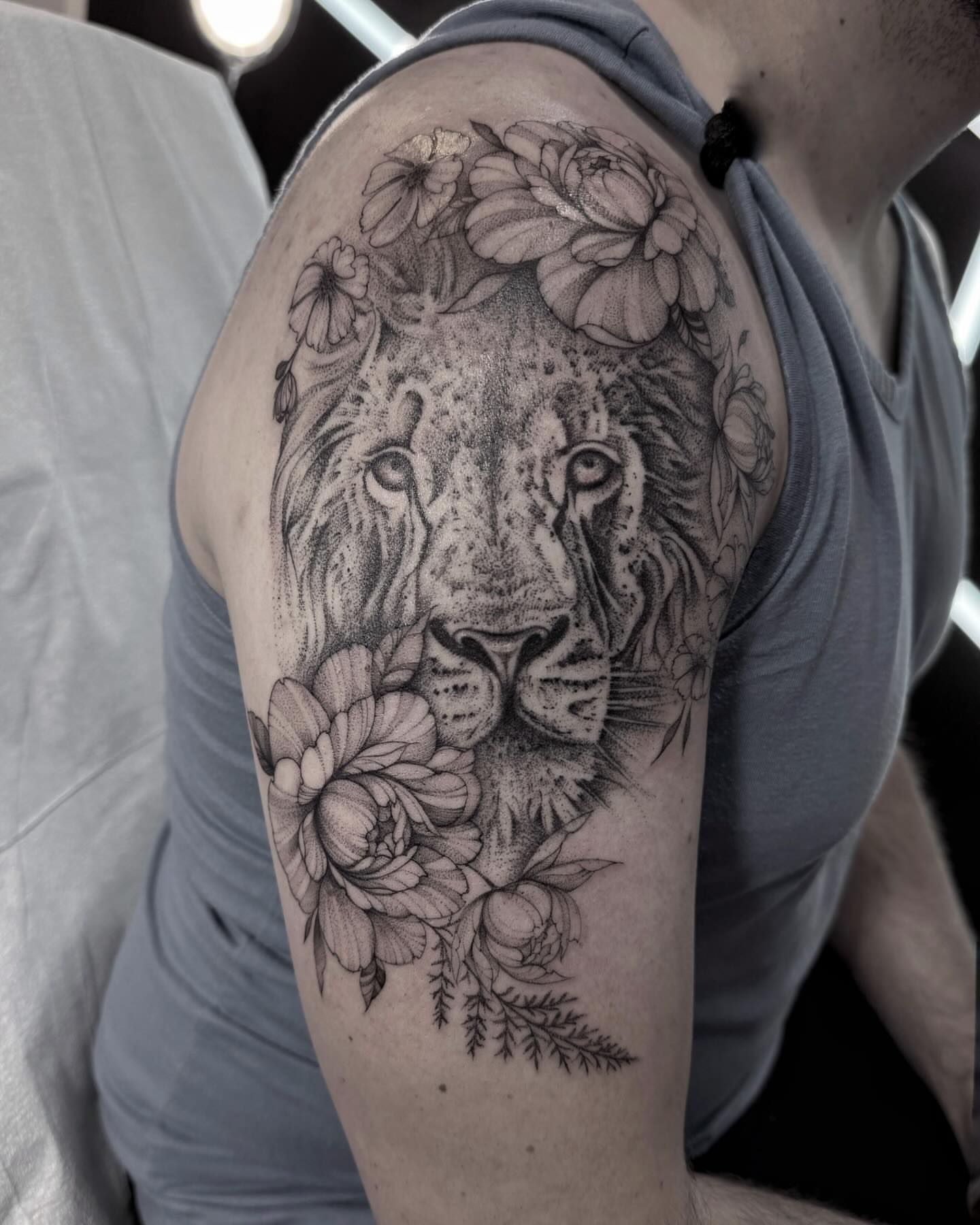 Lion with floral crown dotwork tattoo on the shoulder by Tattoo Yulia Kononenko