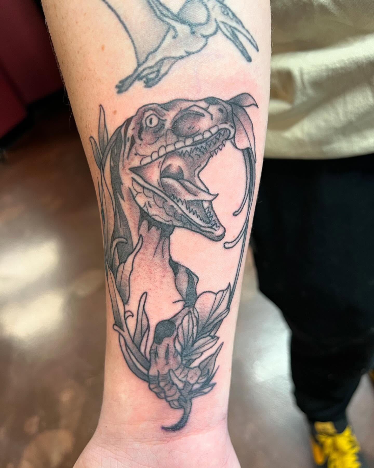 Dinosaur black and grey tattoo on the forearm by Cody Marl