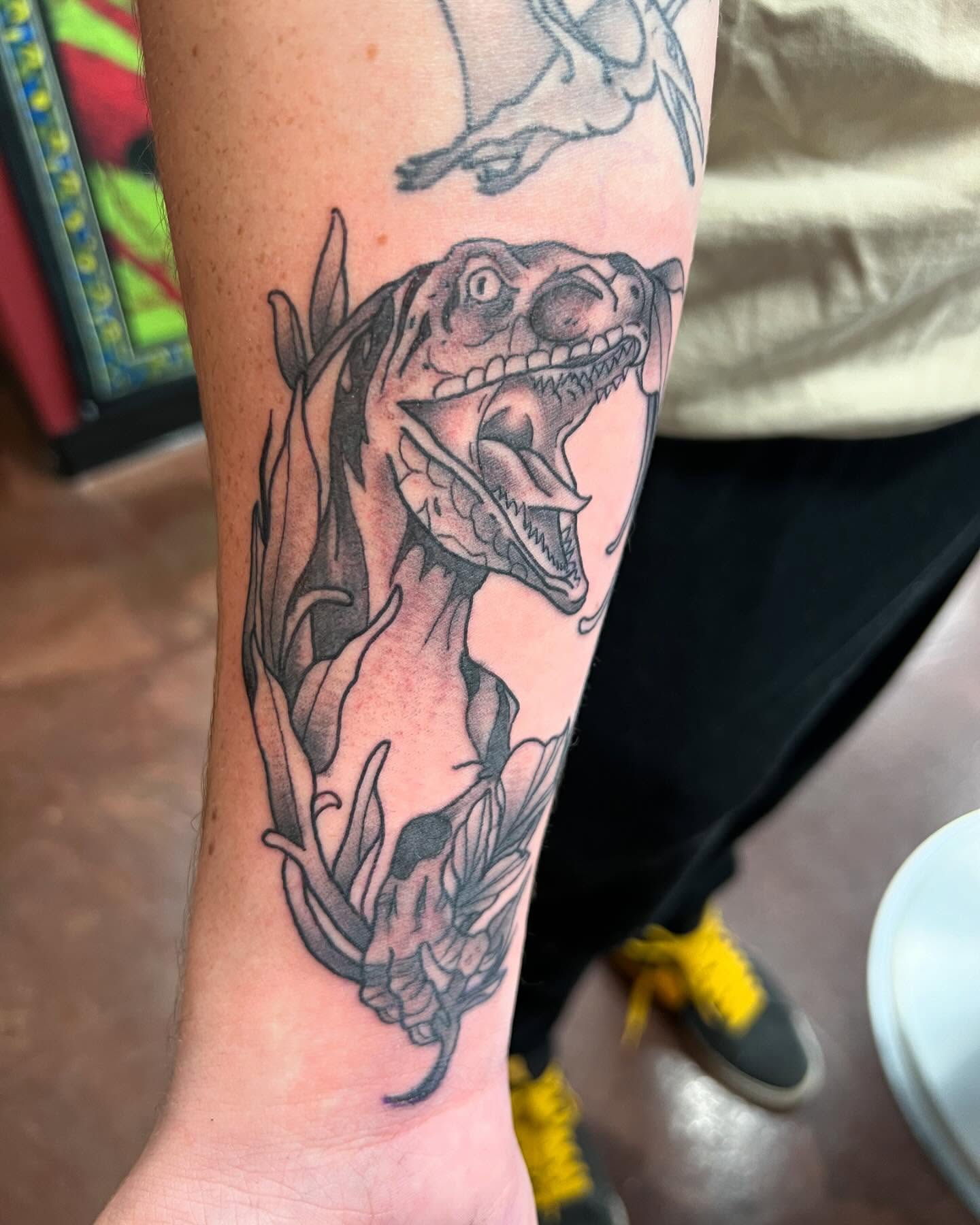 Dinosaur black and grey tattoo on the forearm by Cody Marl