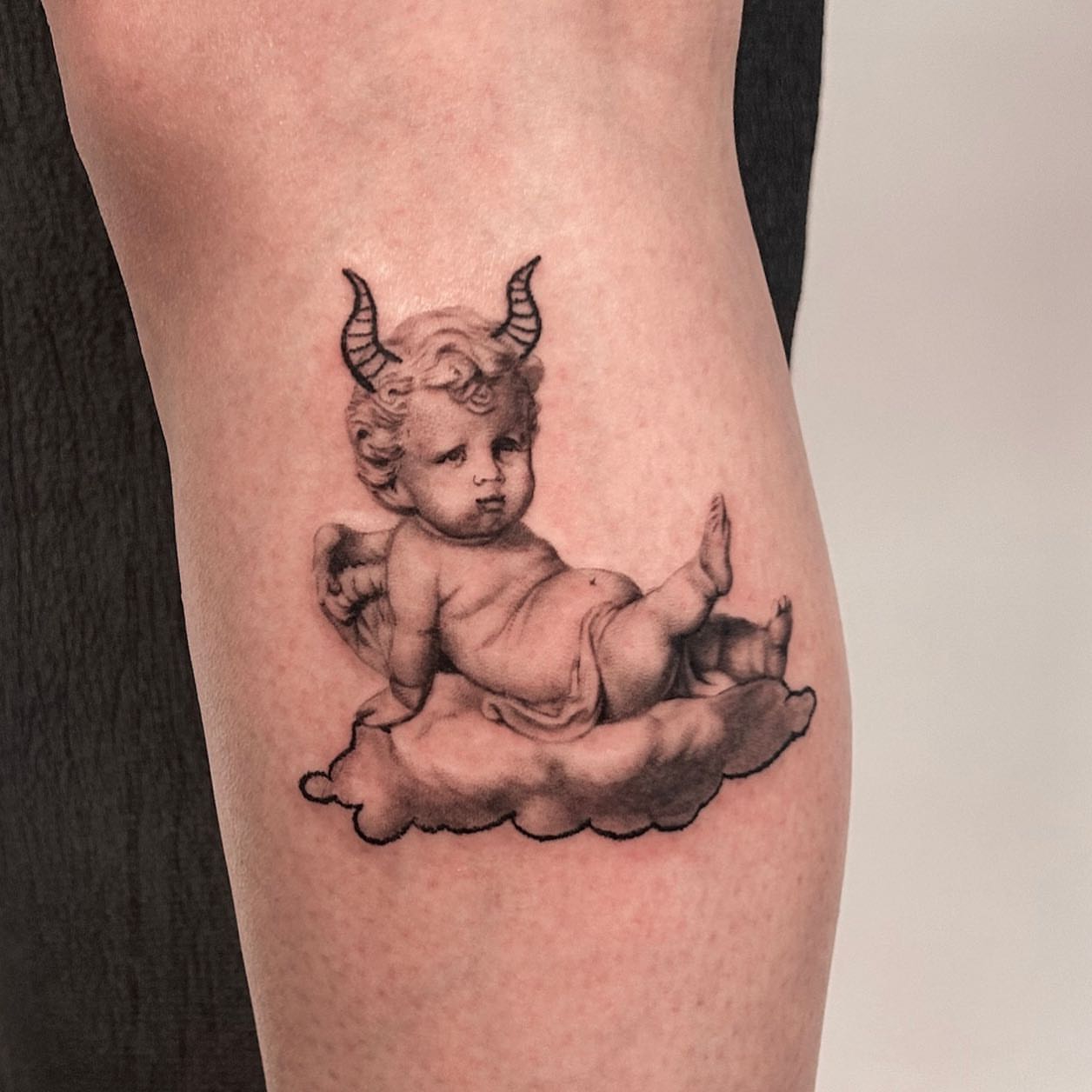 Cherub black and grey tattoo on the thigh by Longtea
