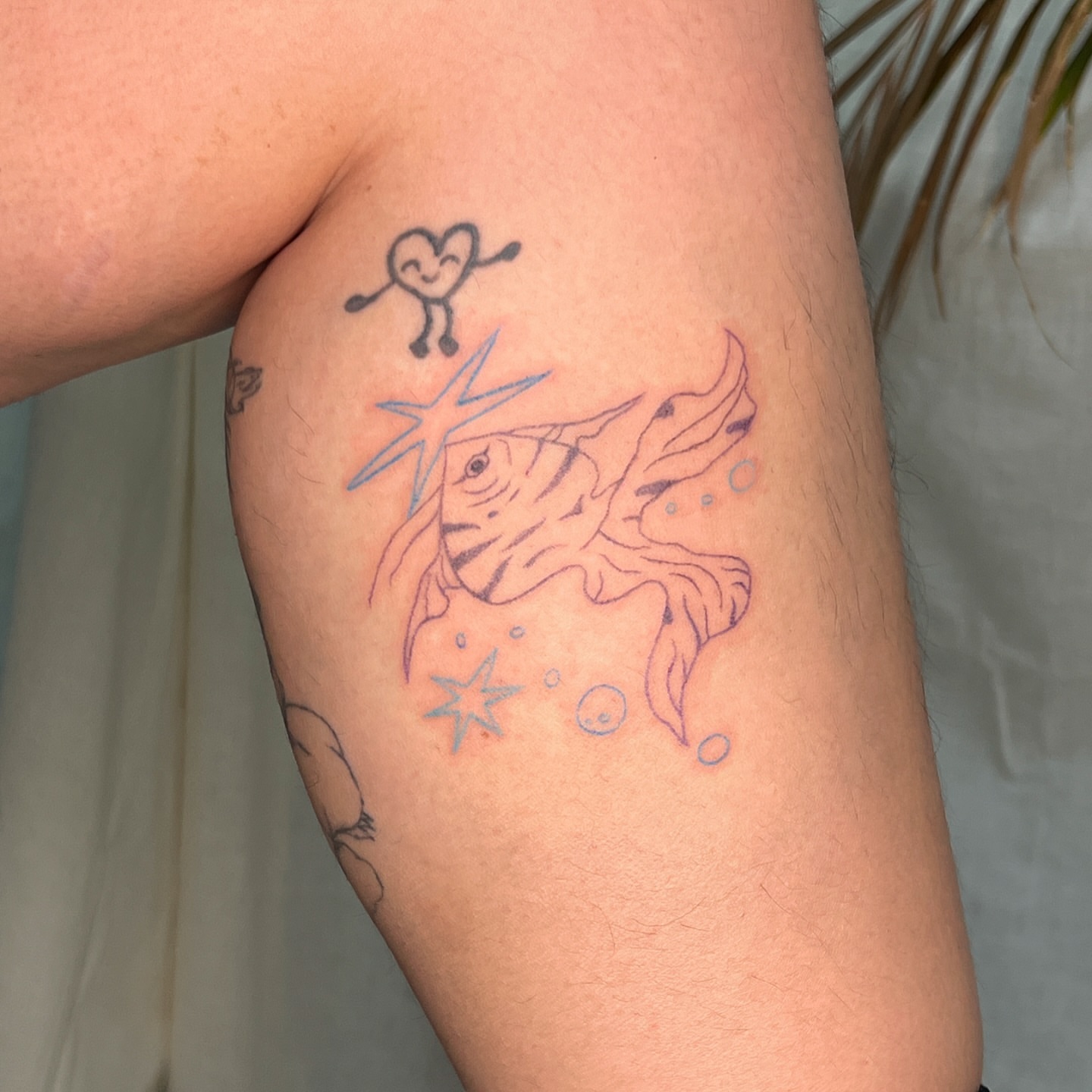 Fish and heart dotwork tattoo on the upper arm by Charlie