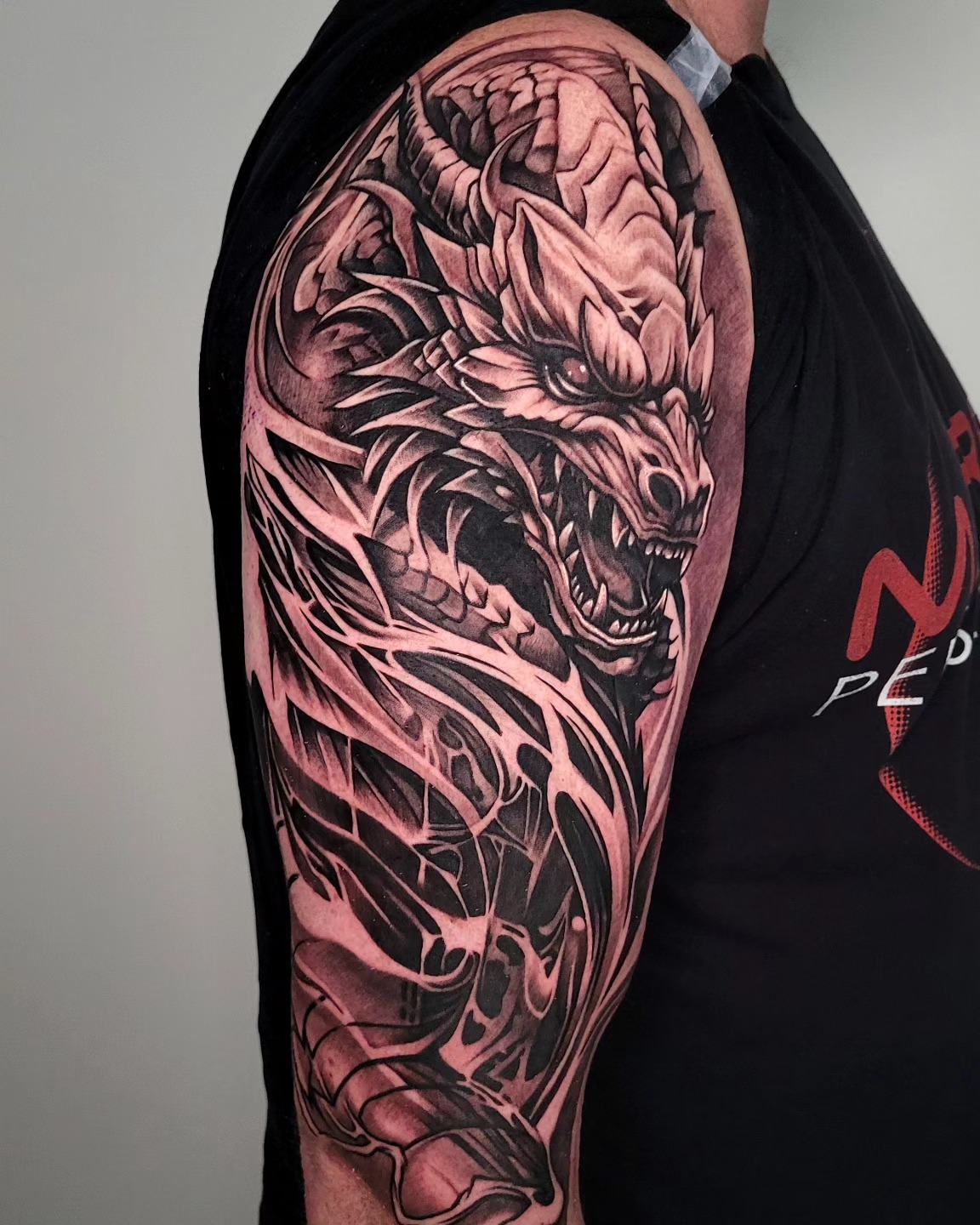 Dragon realism tattoo on the upper arm by Lukasz Olszanski