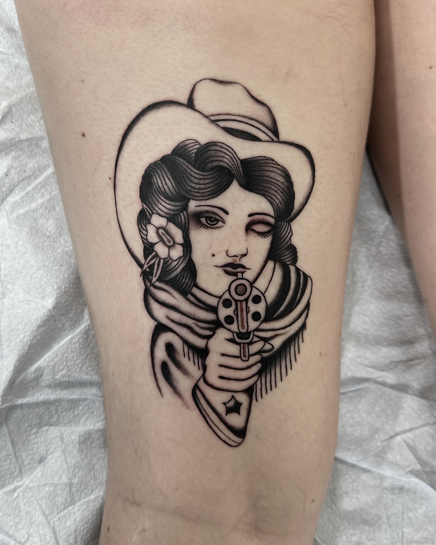 Cowgirl with revolver American traditional tattoo on the thigh by Nicholas Lee, San Francisco, California