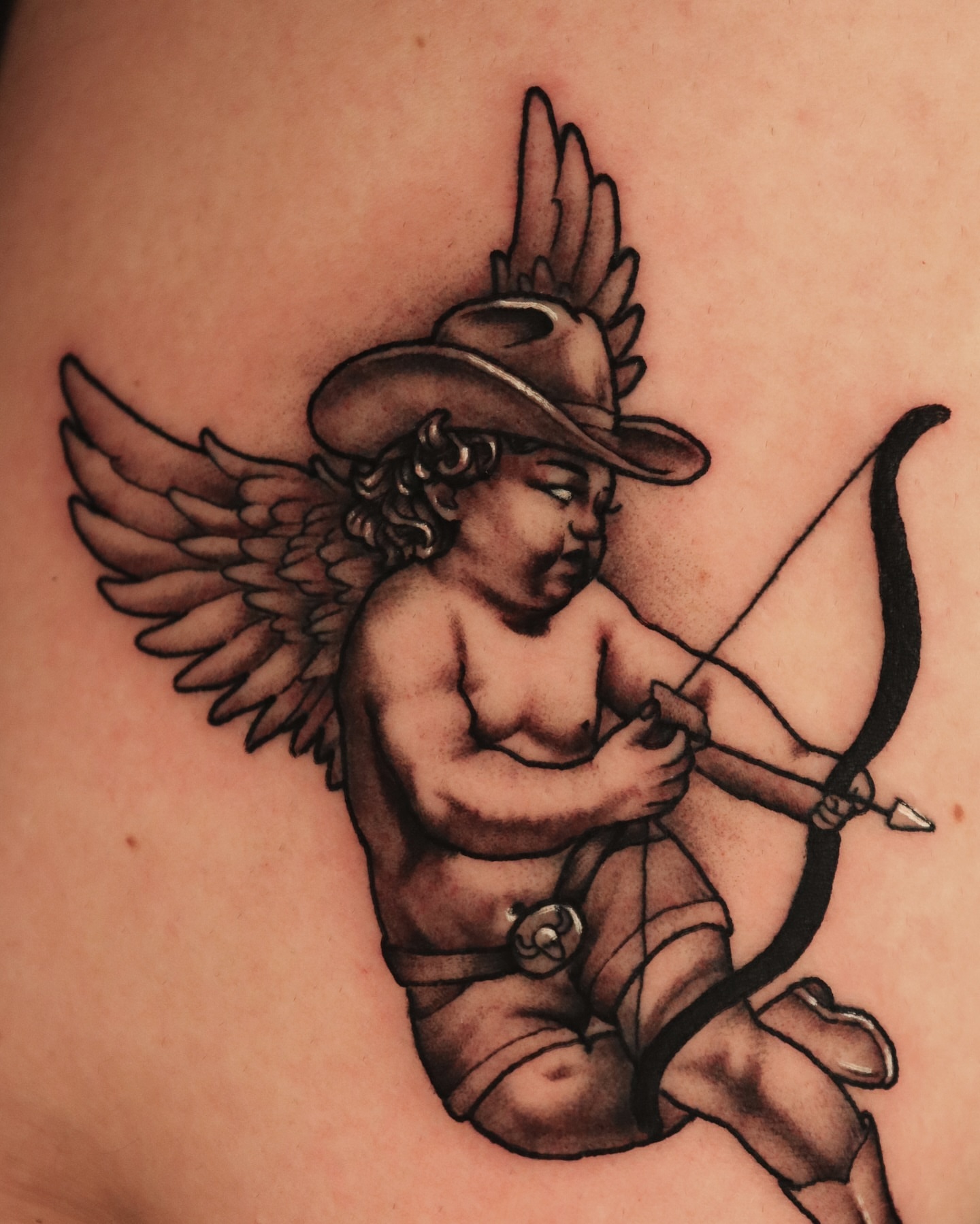 Cupid with bow American traditional tattoo on the thigh by Jeff Reindel