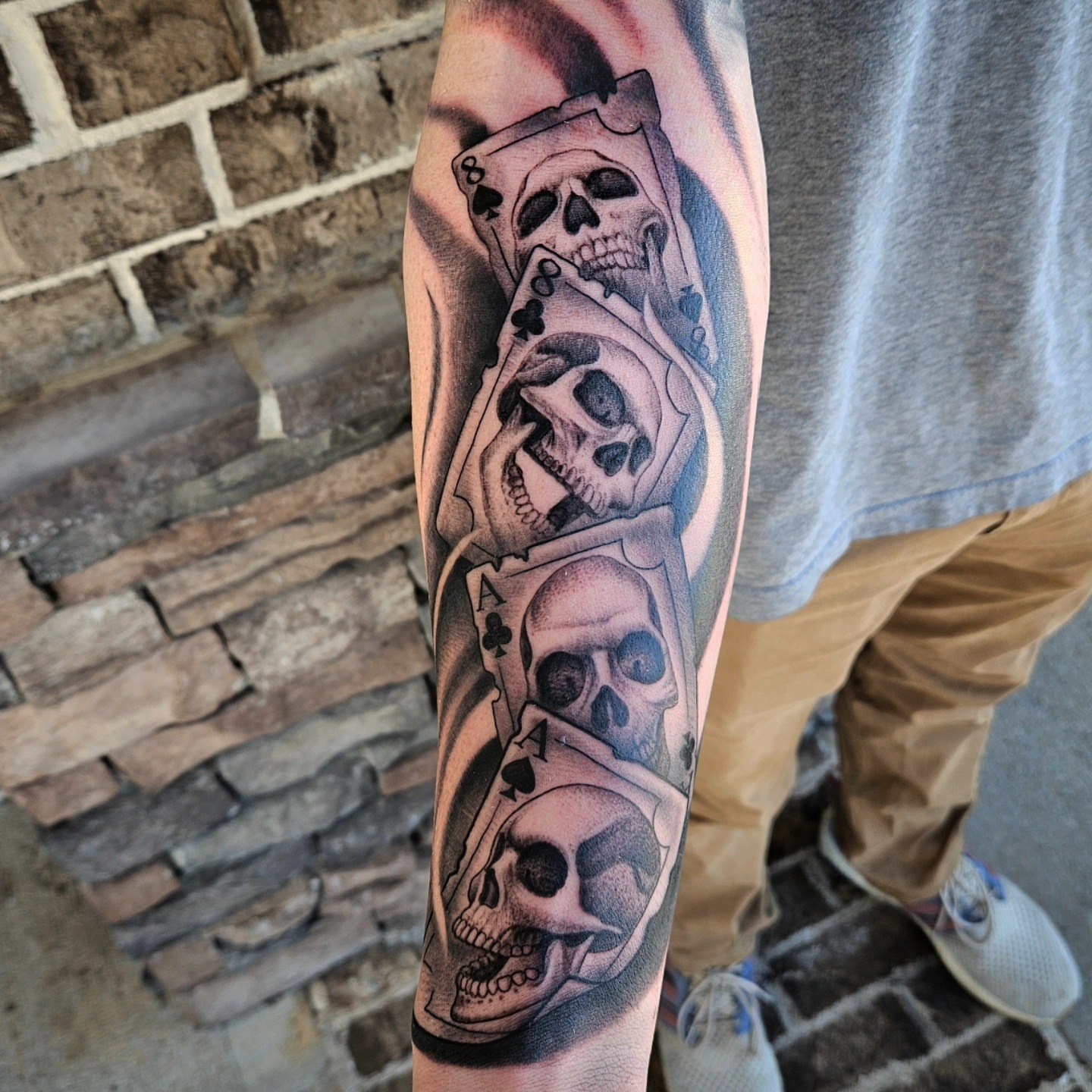 Skulls and playing cards realism tattoo on the forearm by Mike Bugenhagen