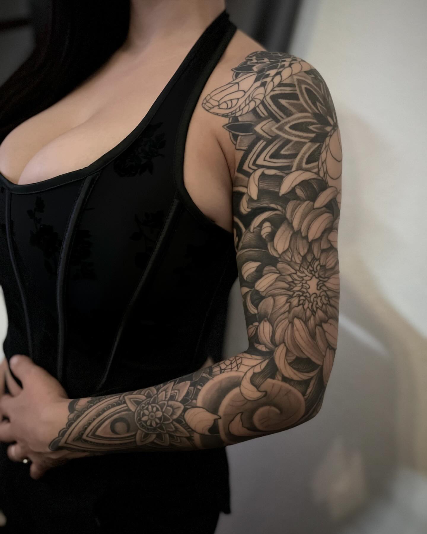 Floral and snake black and grey tattoo on the upper arm by Daniel Gutierrez