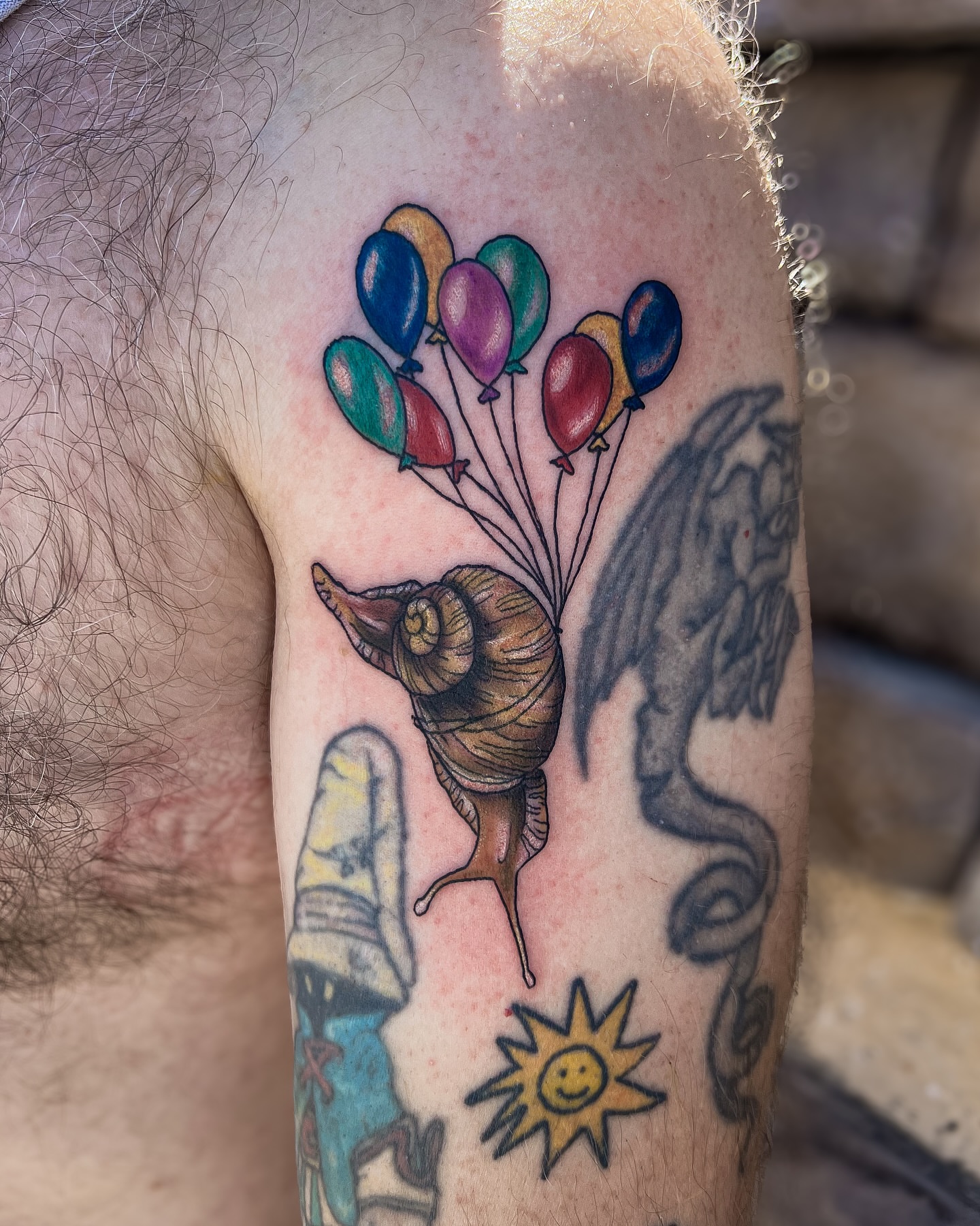Snail with balloons new school tattoo on the forearm by Reagan Sutton