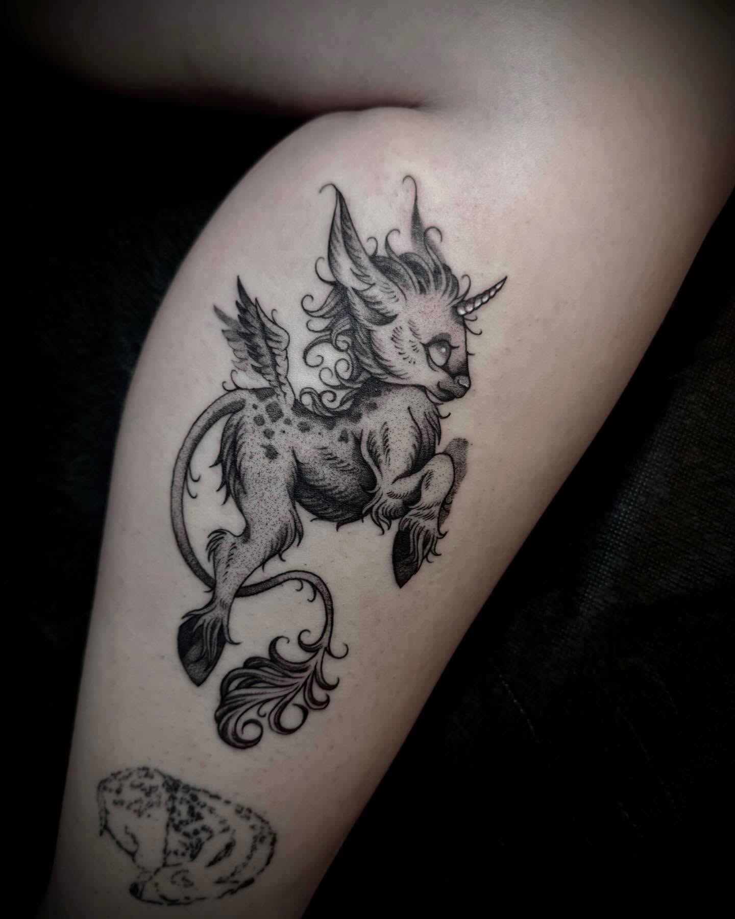 Mythical creature black and grey tattoo on the thigh by Melanie