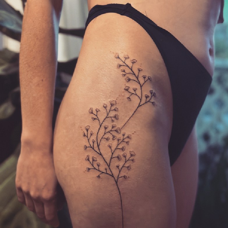 Flower branch fine line tattoo on the thigh by Gaya