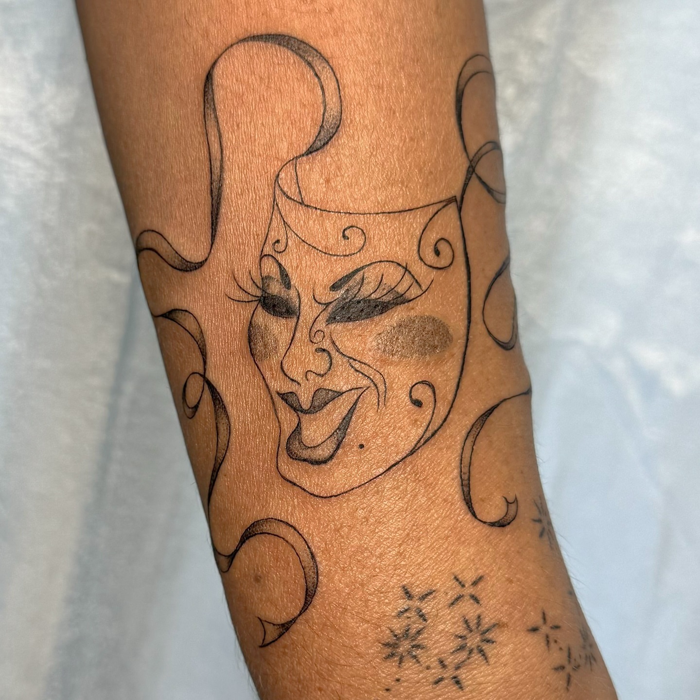Mask black and grey tattoo on the forearm by RyAnn Lynn
