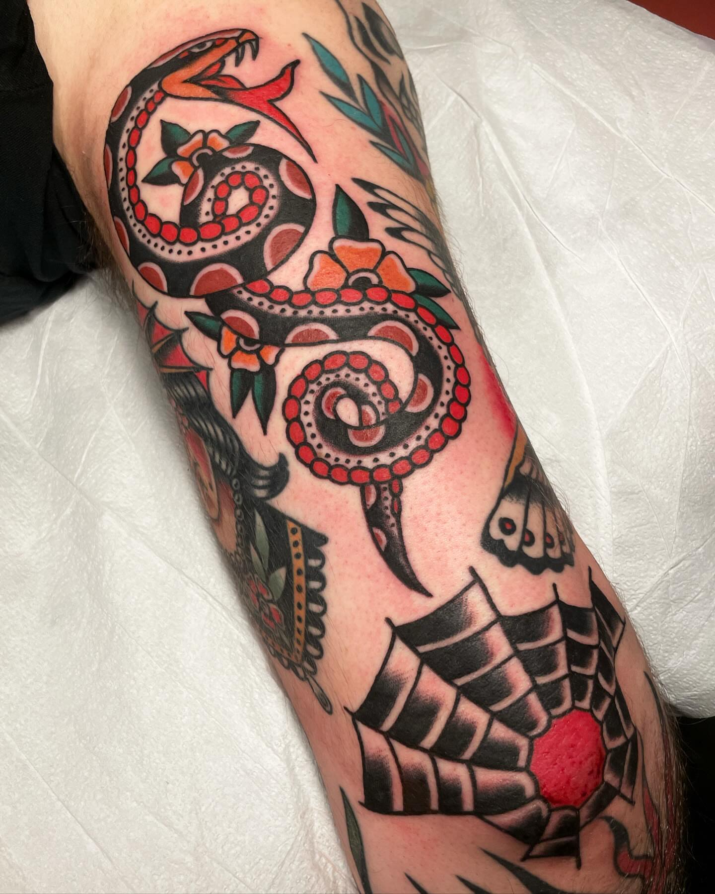 Snake and flowers American traditional tattoo on the forearm by Mike Hudgins