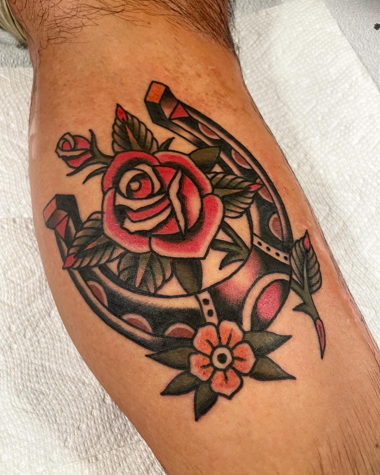 Rose and horseshoe American traditional tattoo on the thigh by Mike Hudgins
