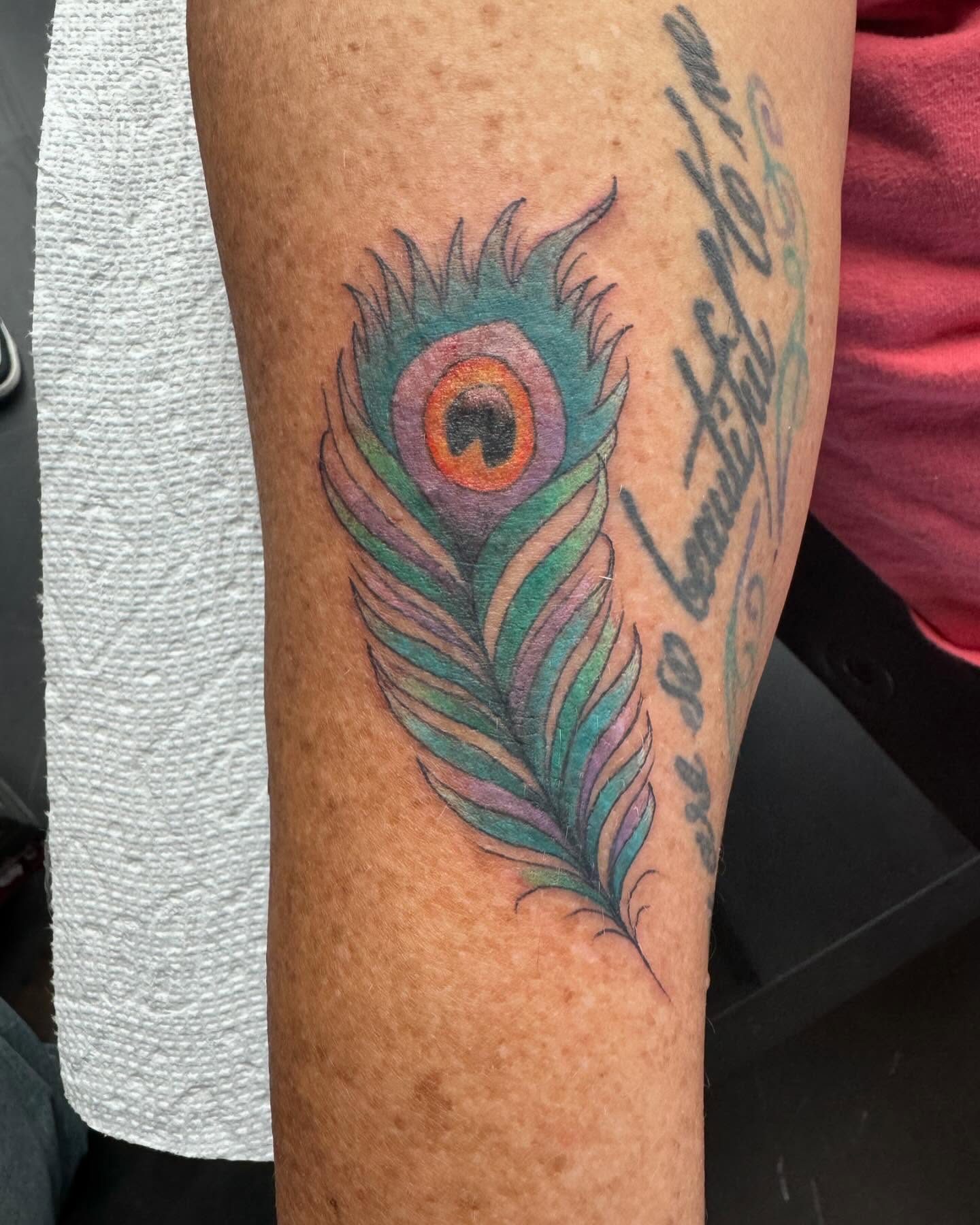 Peacock feather new school tattoo on the forearm by Bobby Hurst