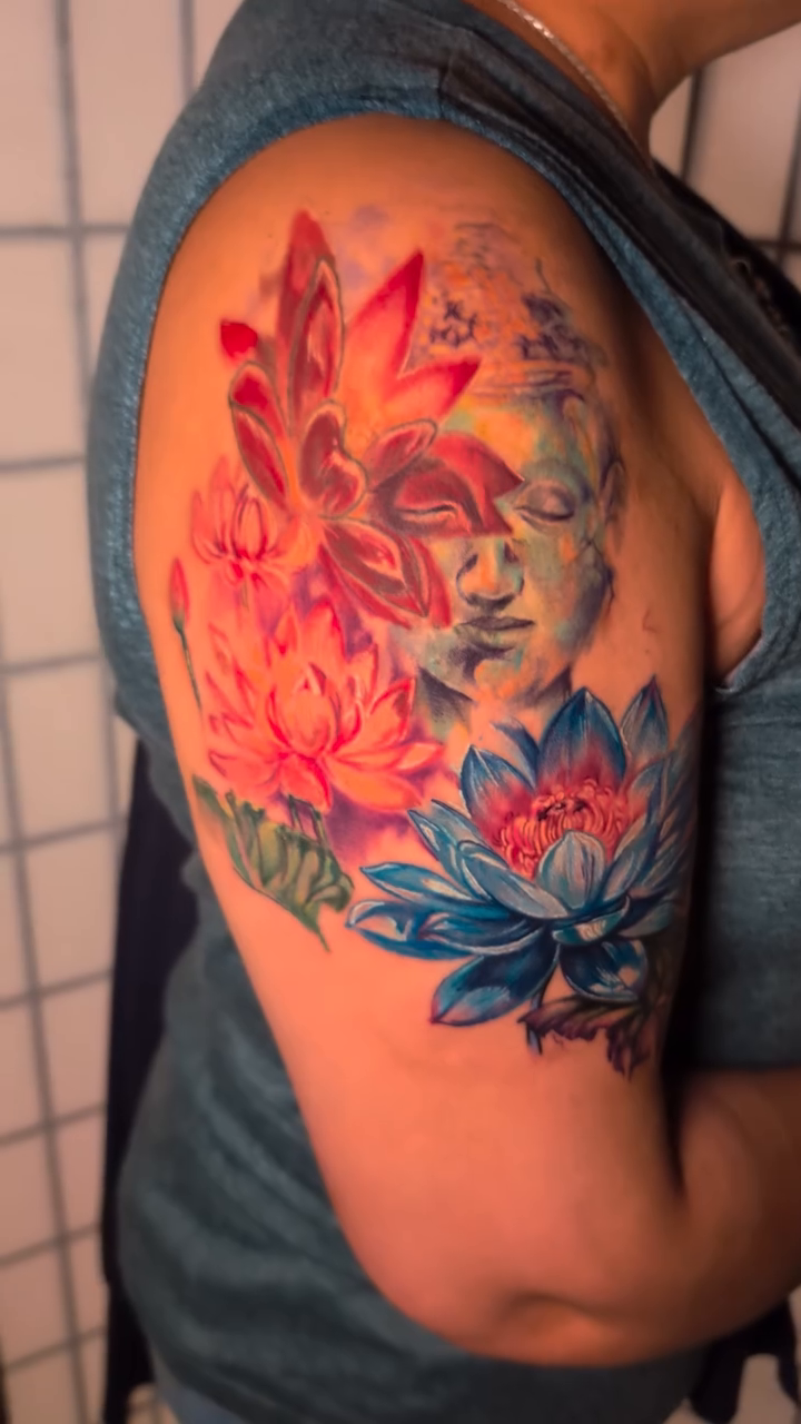 Buddha face with lotus flowers realism tattoo by Colorful Tattoos by Cody Dean