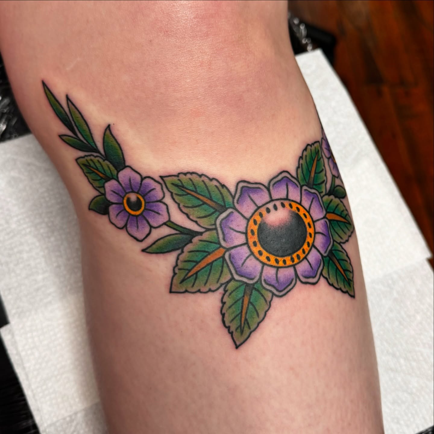 Purple flowers American traditional tattoo on the forearm by kenneth nash