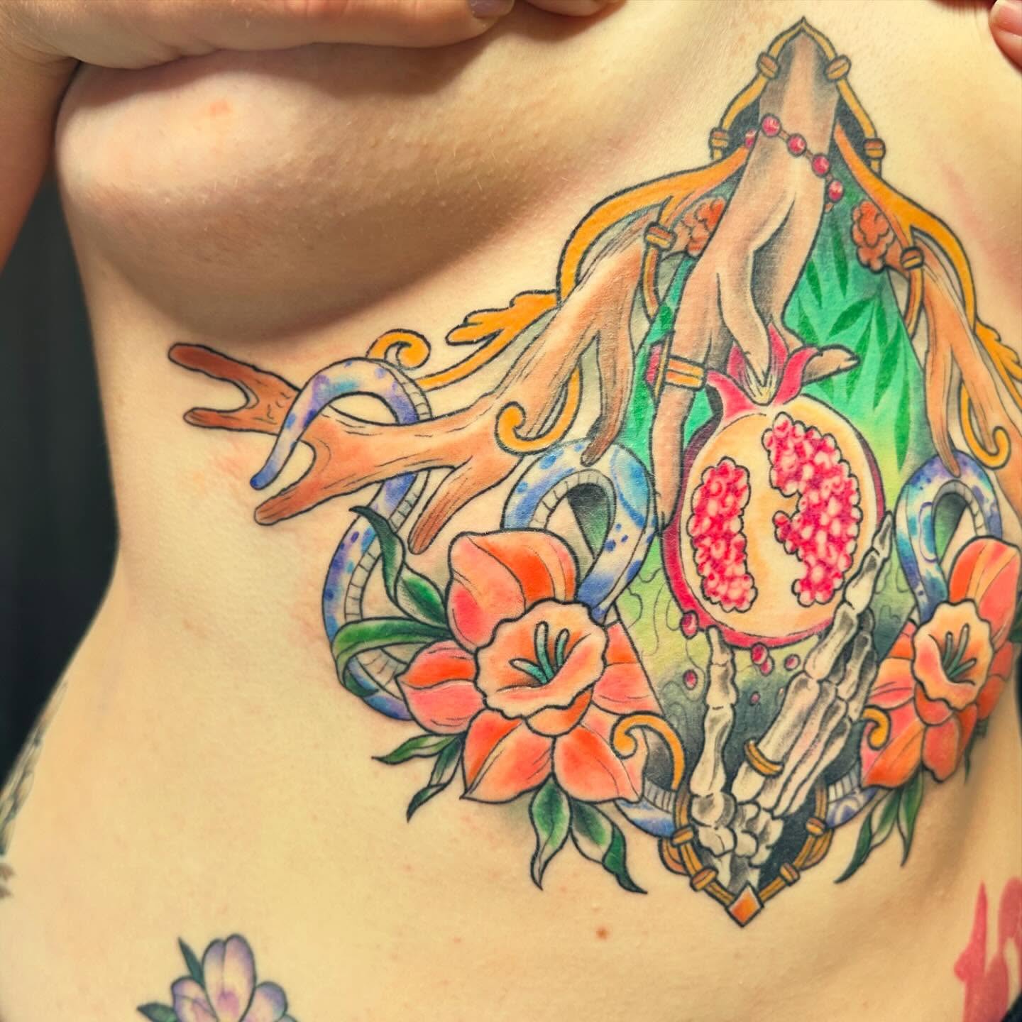 Pomegranate and skeleton hand watercolor tattoo on the torso by Halle Haas