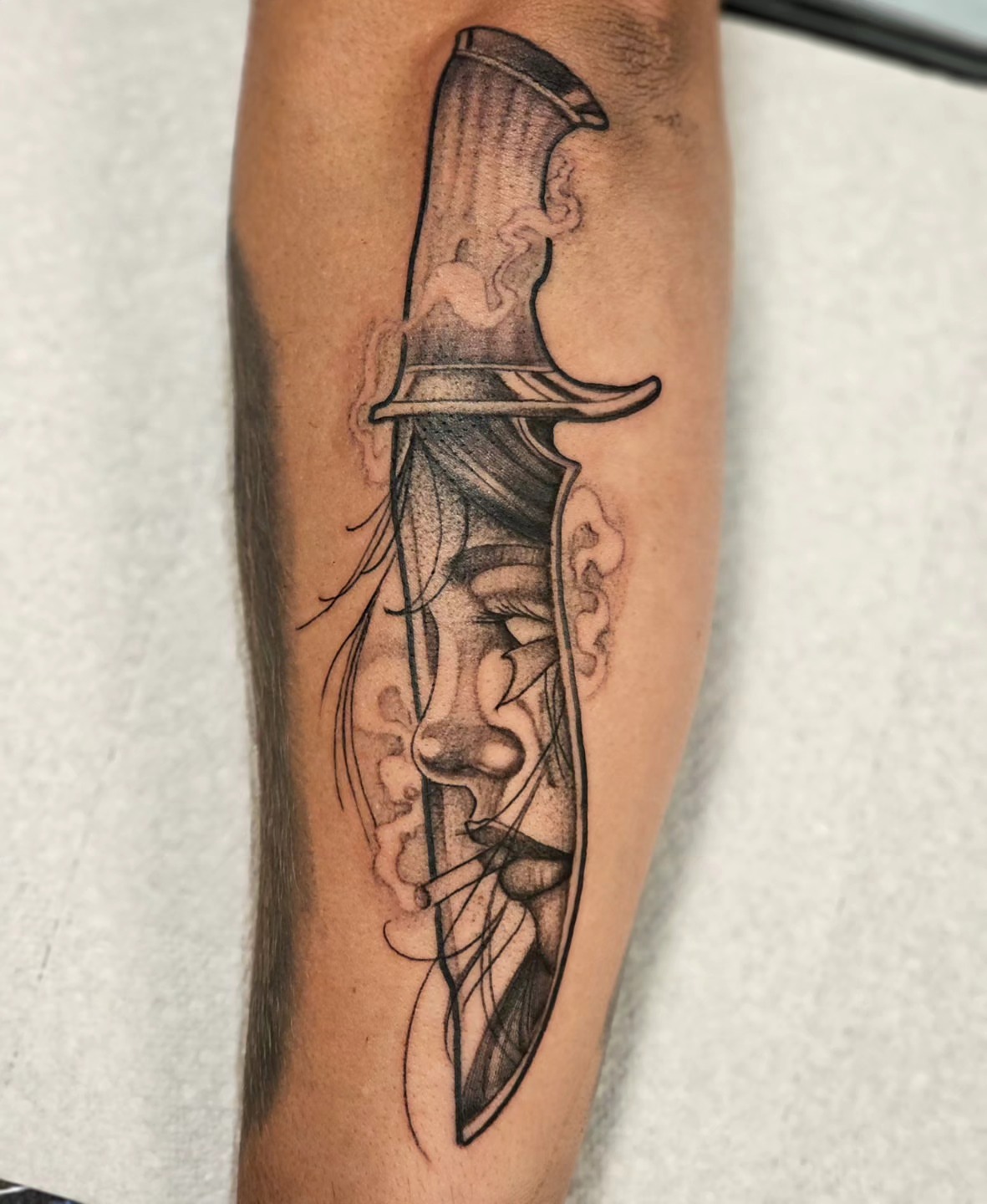 Knife and face realism tattoo on the forearm by TattoosbyPhatboi