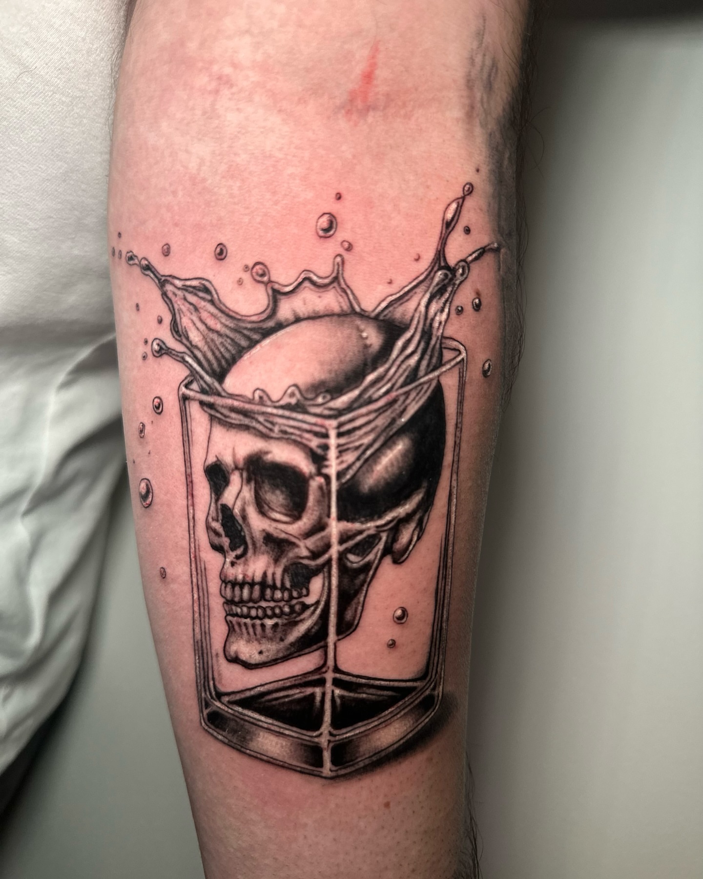 Skull in glass realism tattoo on the forearm by Héctor Agudelo