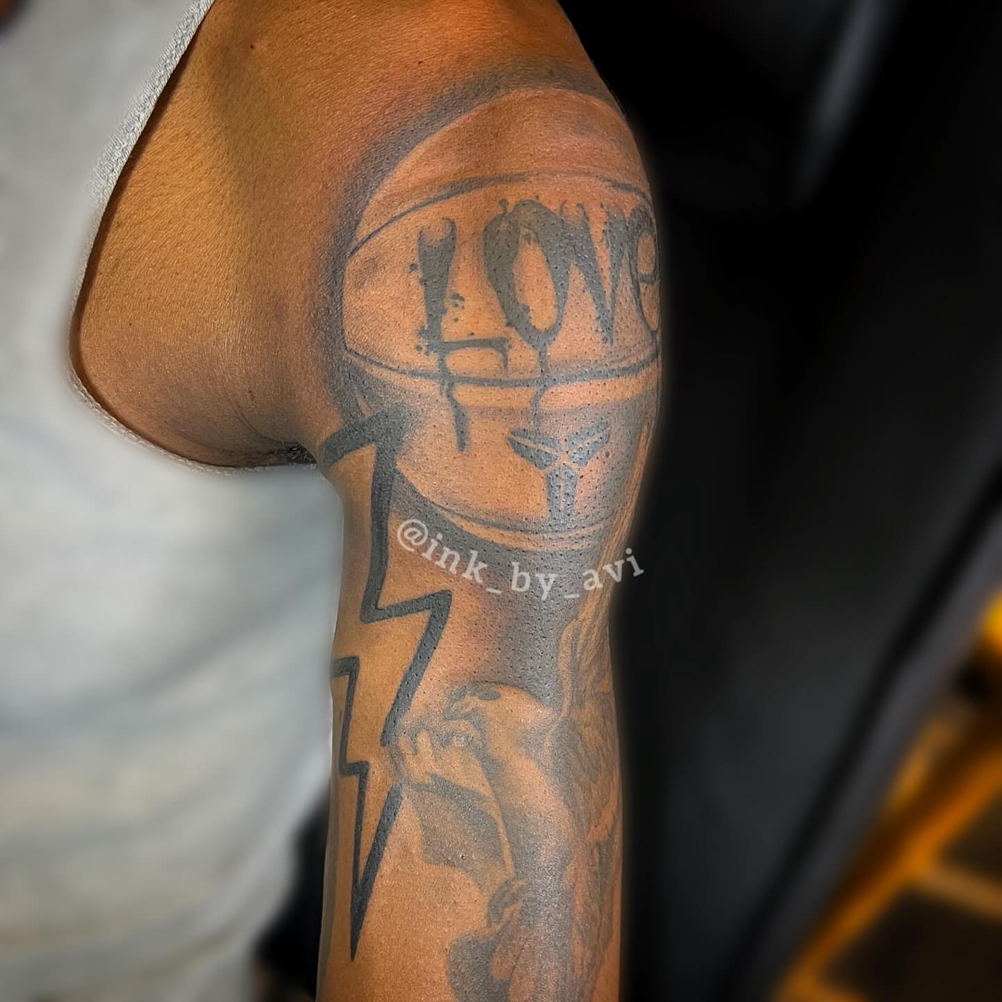 Helmet with 'LOVE' black and grey tattoo on the upper arm by Avi, Cleveland, Ohio
