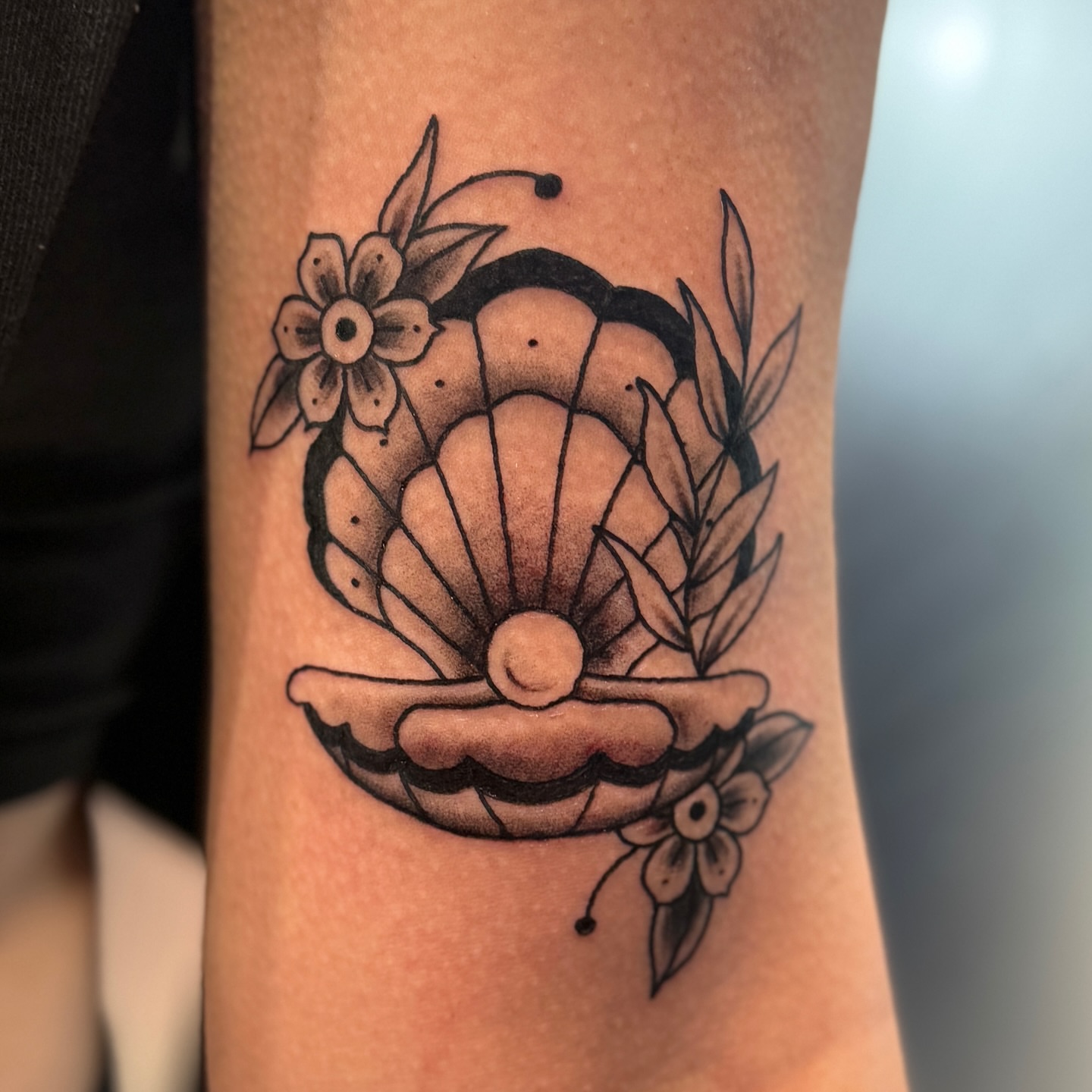 Shell and flowers black and grey tattoo on the forearm by Ashley Rose - Minnesota Tattoo Artist