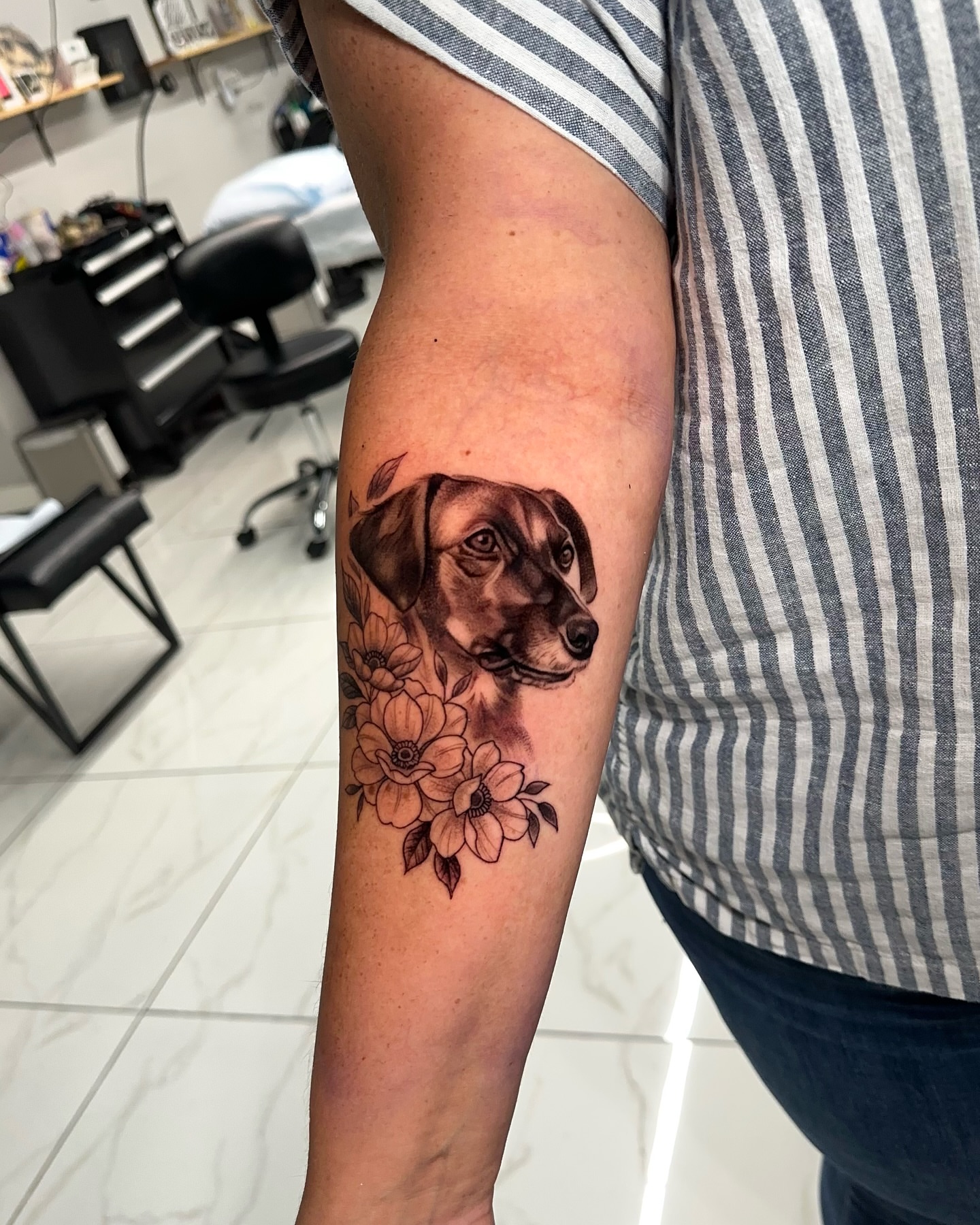 Dog with flowers realism tattoo on the forearm by Joey Hella Tattoo Artist