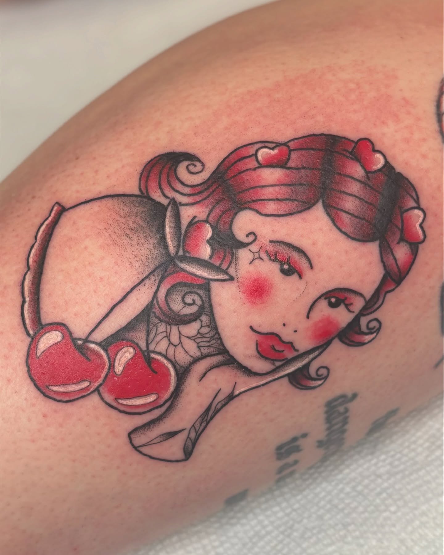 Pin-up girl American traditional tattoo on the upper arm by Bridget Smith