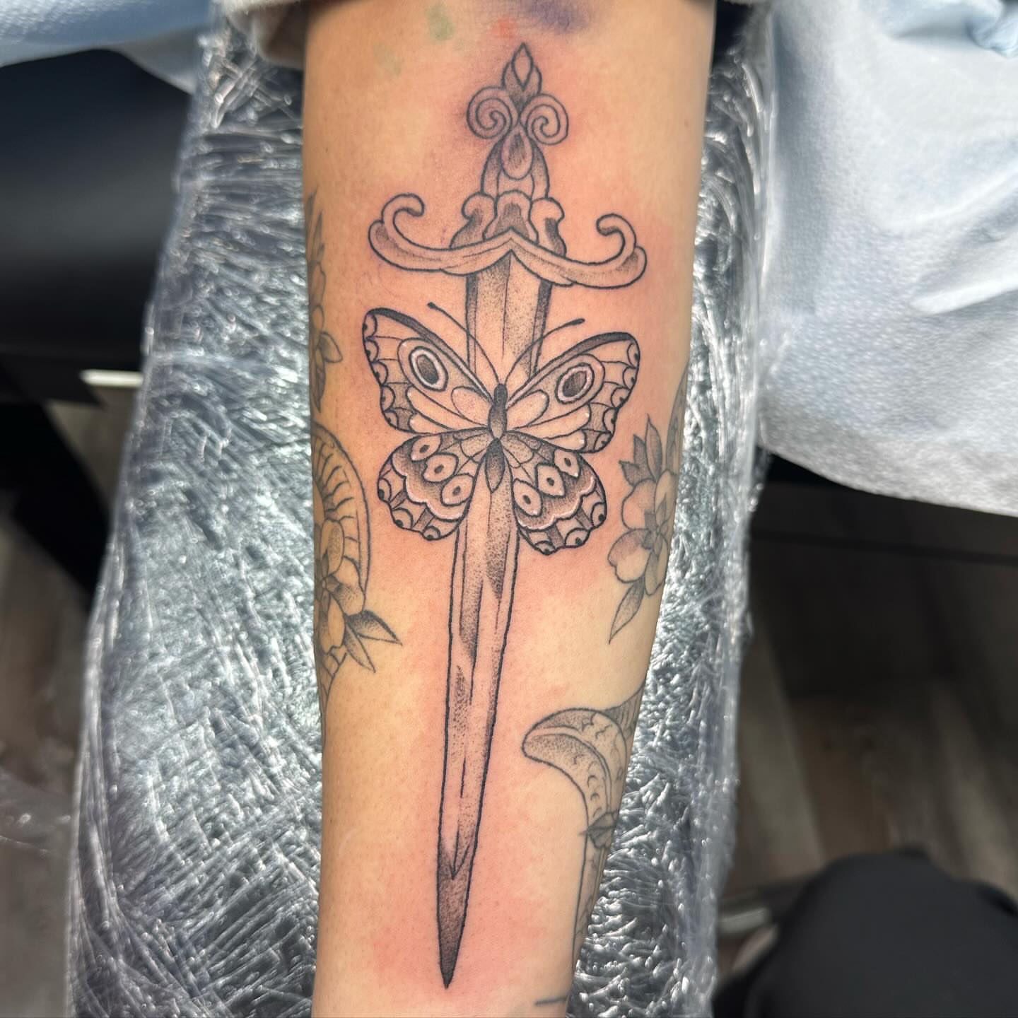 Sword and butterfly black and grey tattoo on the forearm by Halle Haas