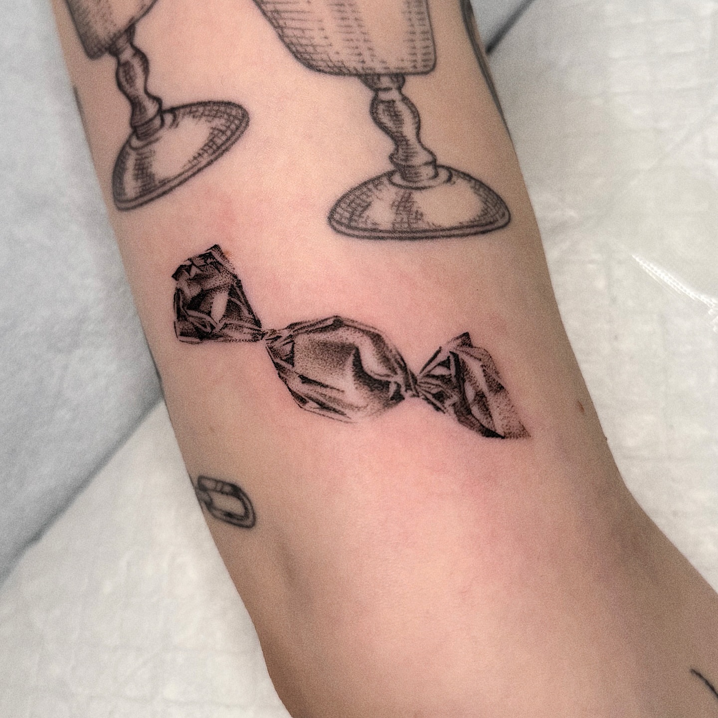 Candy black and grey tattoo on the forearm by Jenni Palomaa