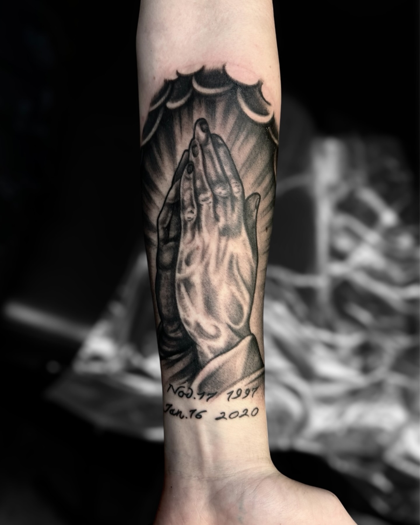 Praying hands black and grey tattoo on the forearm by Tattoos by Dave