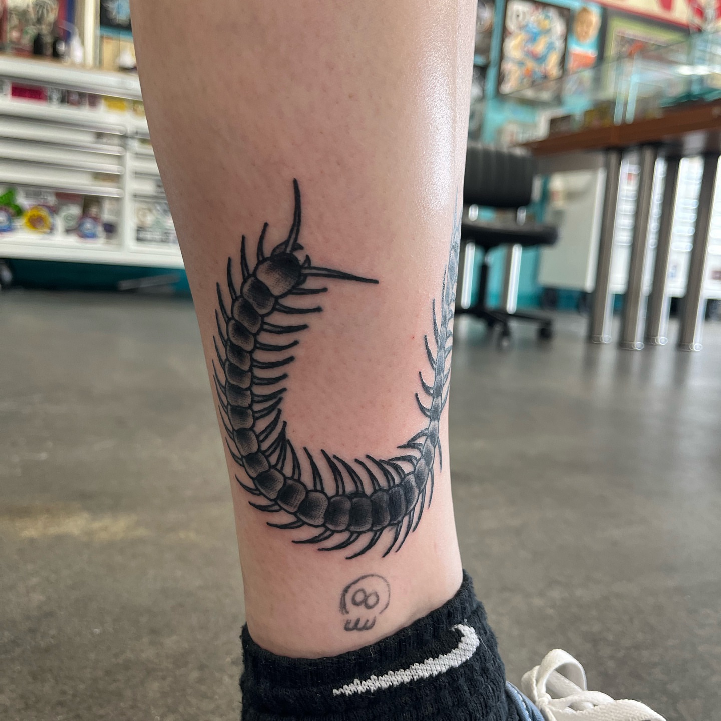 Centipede black and grey tattoo on the forearm by Ashley Camp