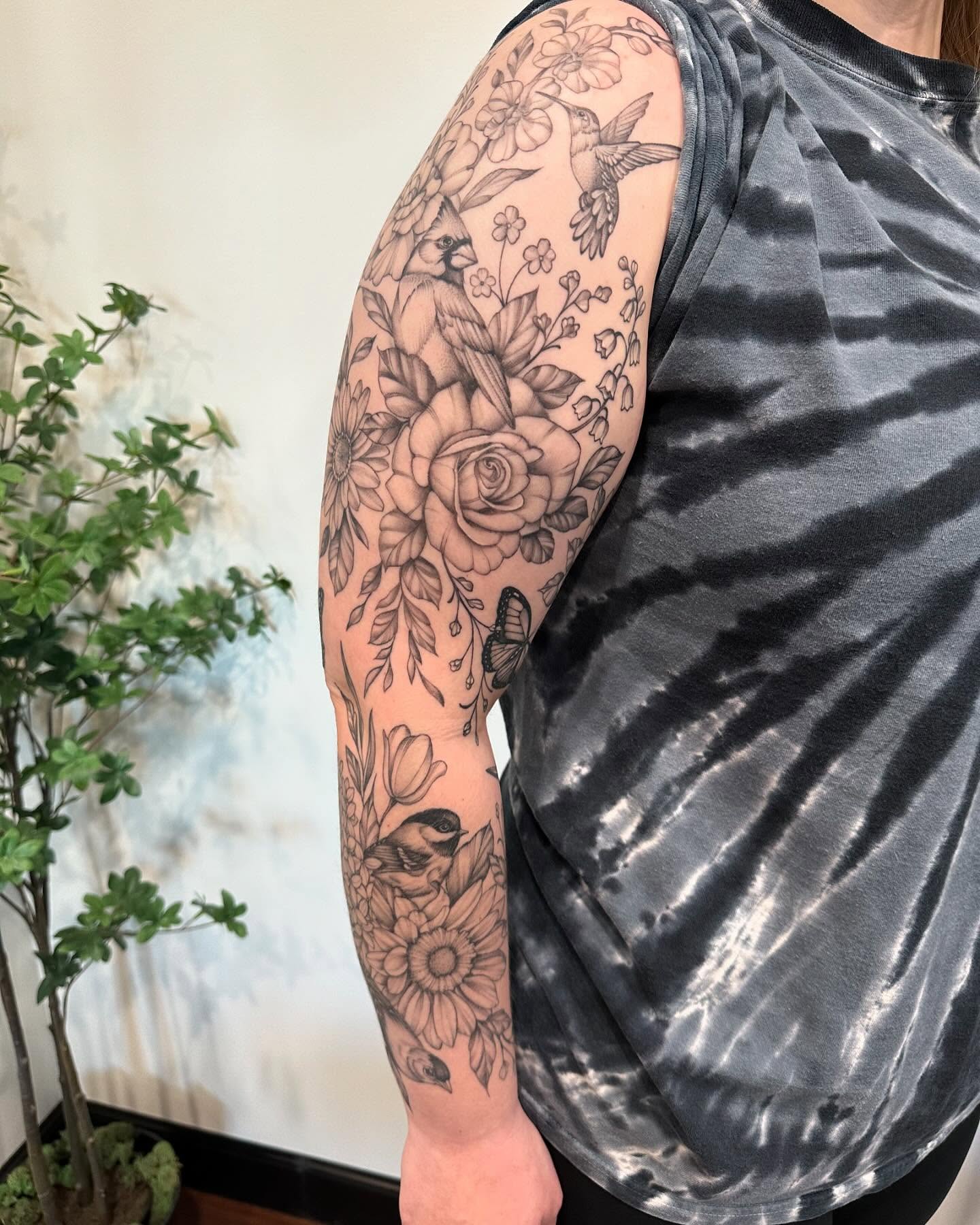 Floral and bird realism tattoo on the upper arm by Kate Darling