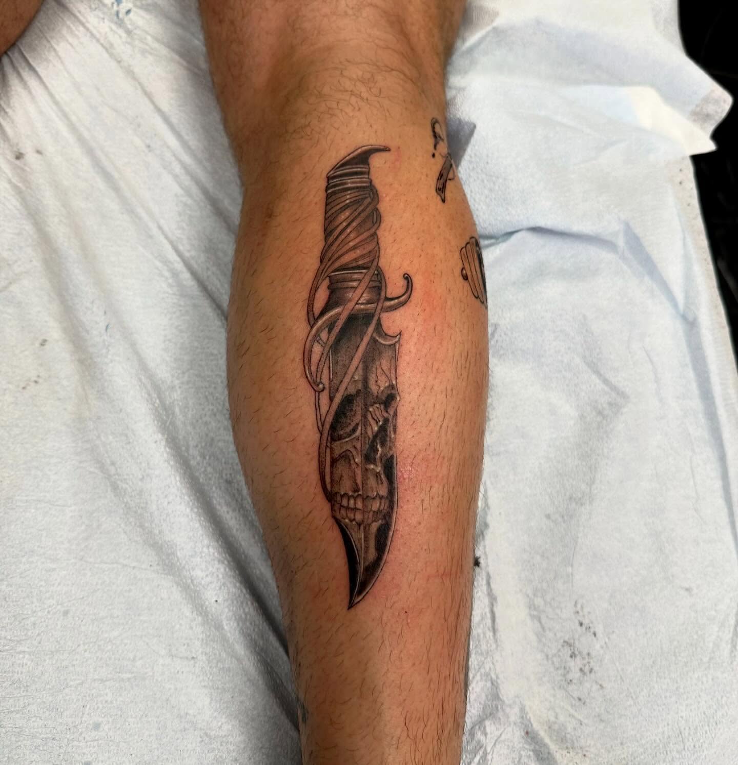 Knife with skull black and grey tattoo on the forearm by Amber Lynn