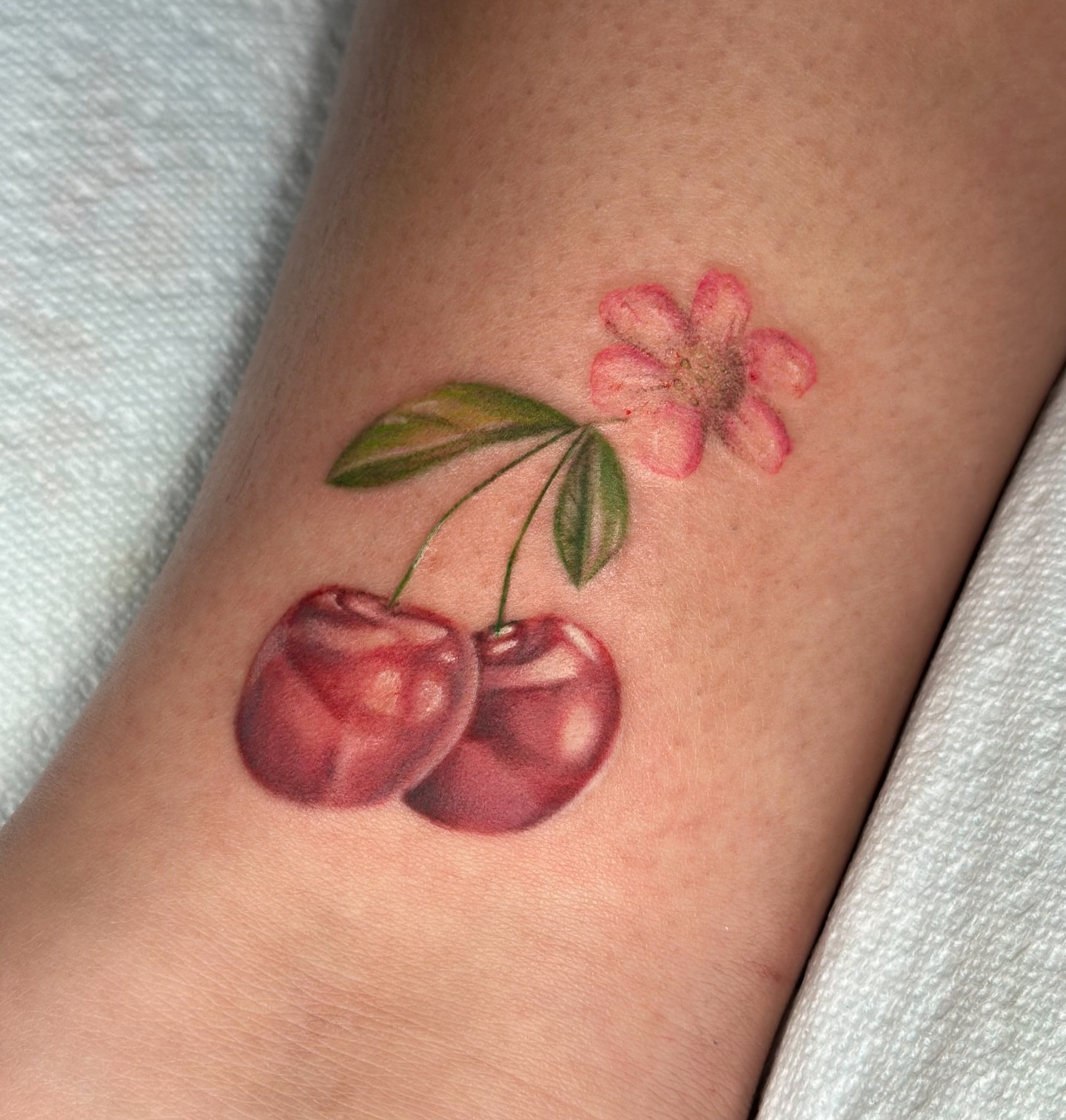 Cherries and flower realism tattoo on the forearm by zoe mars