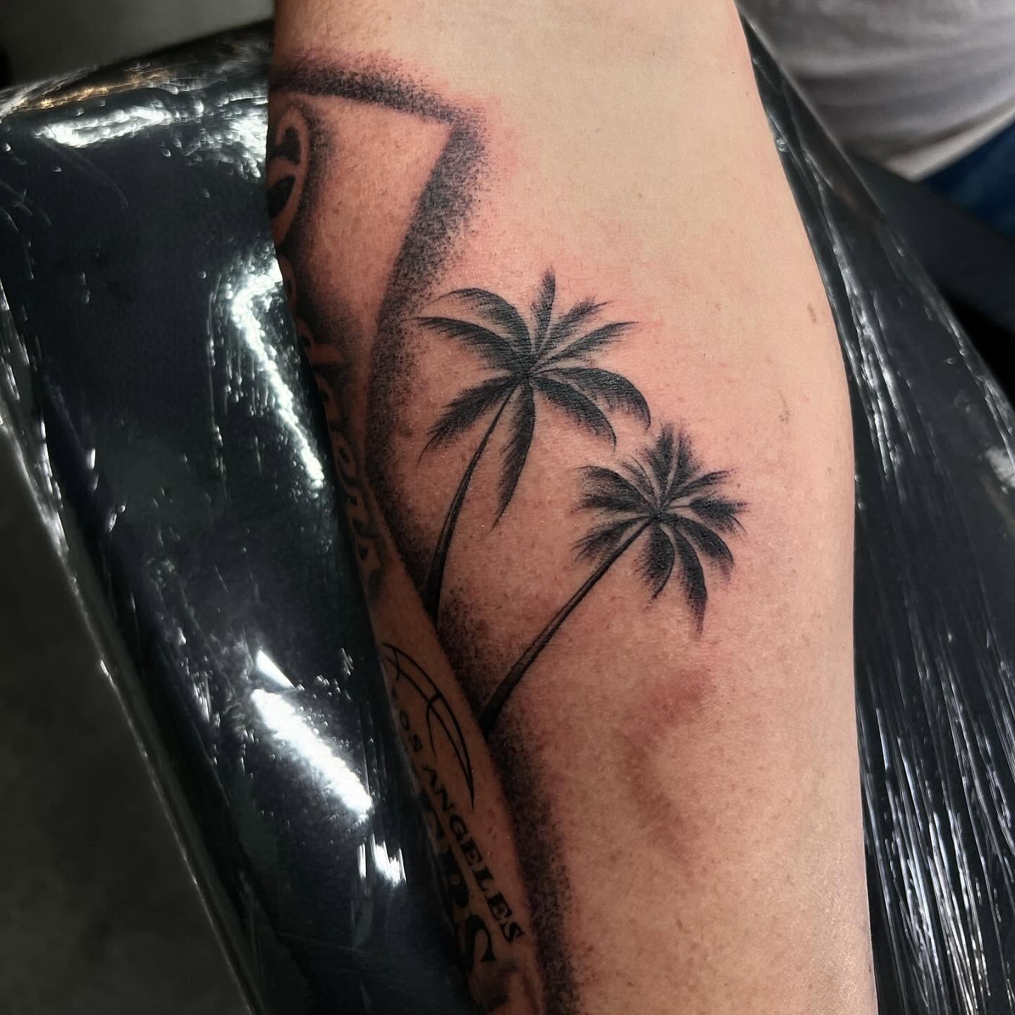 Palm trees black and grey tattoo on the forearm by Joey Moreno