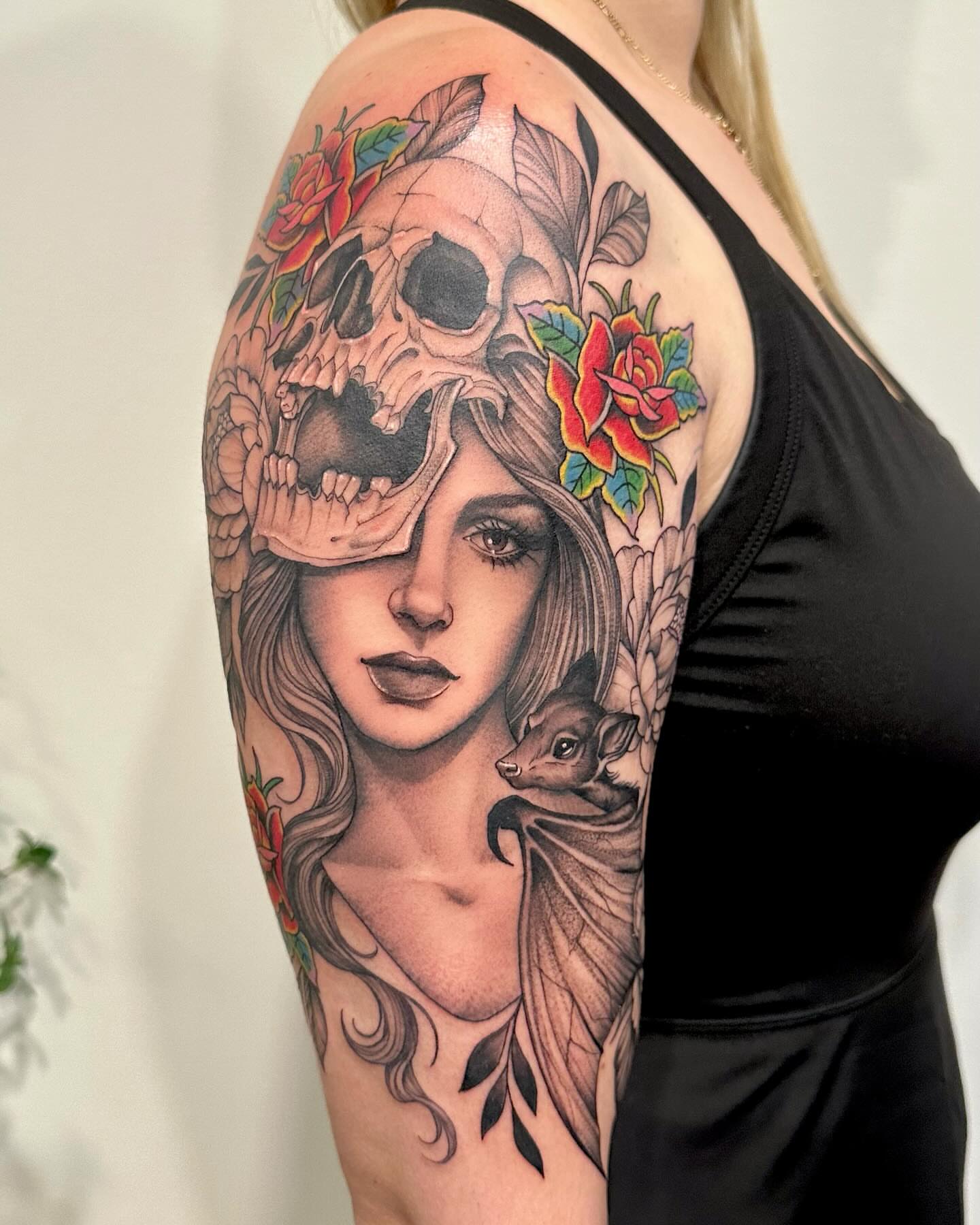 Woman with skull and flowers realism tattoo on the upper arm by Kate Darling