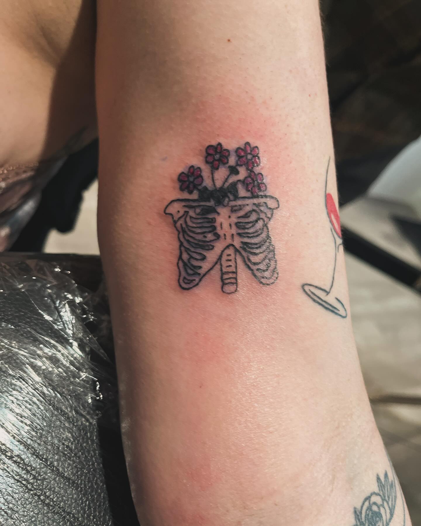 Rib cage with flowers black and grey tattoo on the forearm by Anna DeLuna