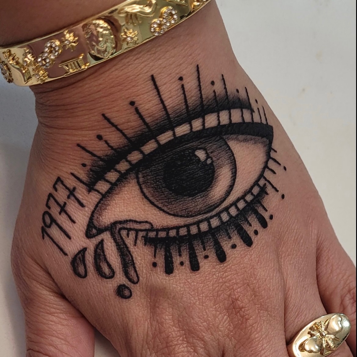 Eye with tears black and grey tattoo on the hand by Diana